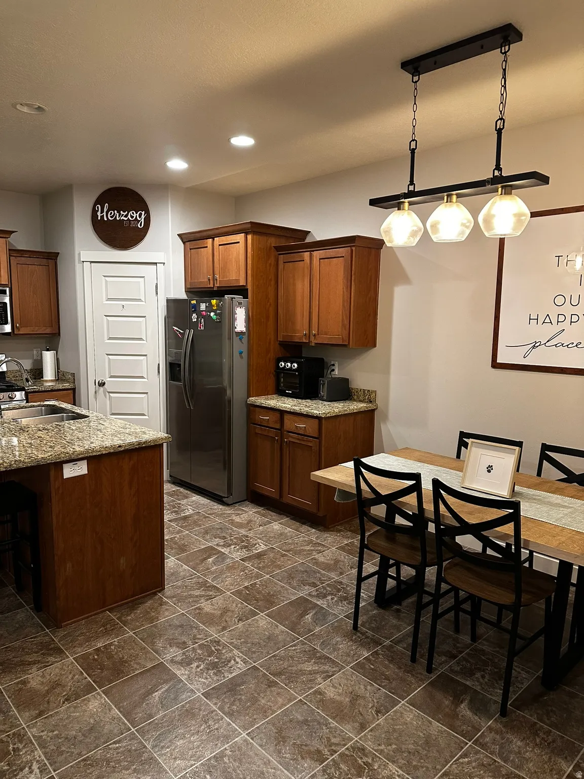 Kitchen and dining area featuring wood-finish cabinetry, granite-style countertops, and tile flooring