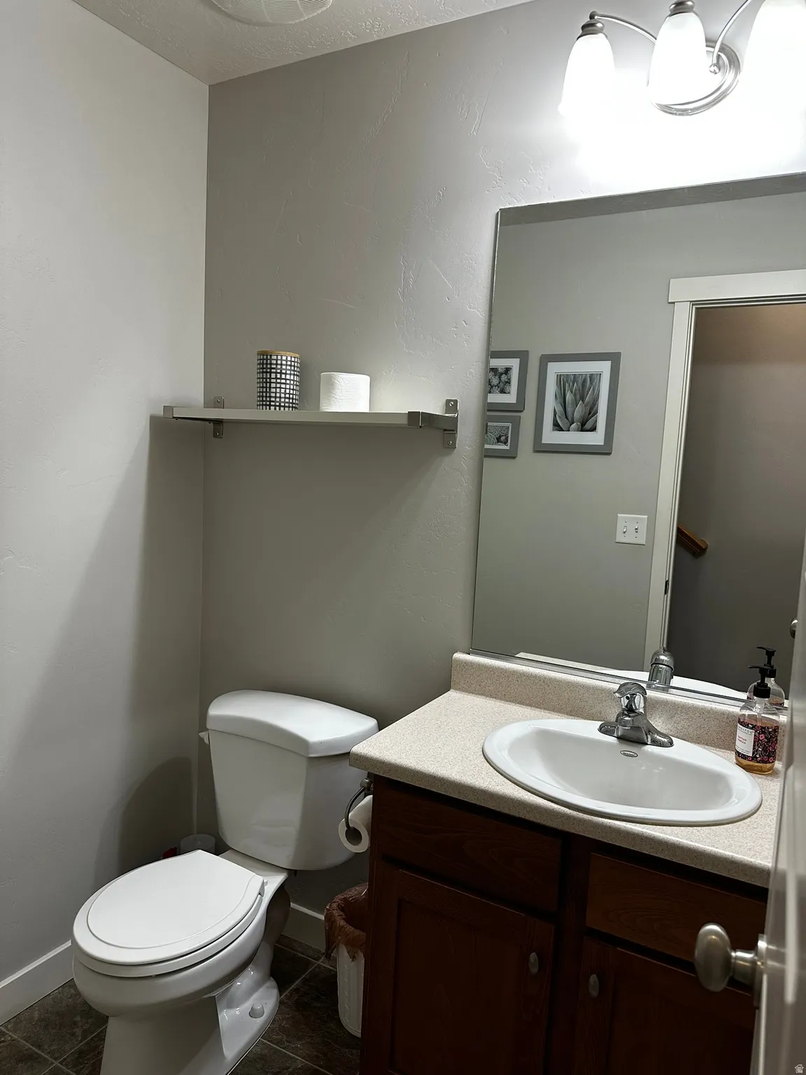 Compact bathroom featuring a vanity with a laminate countertop, integrated sink, and an expansive mirror