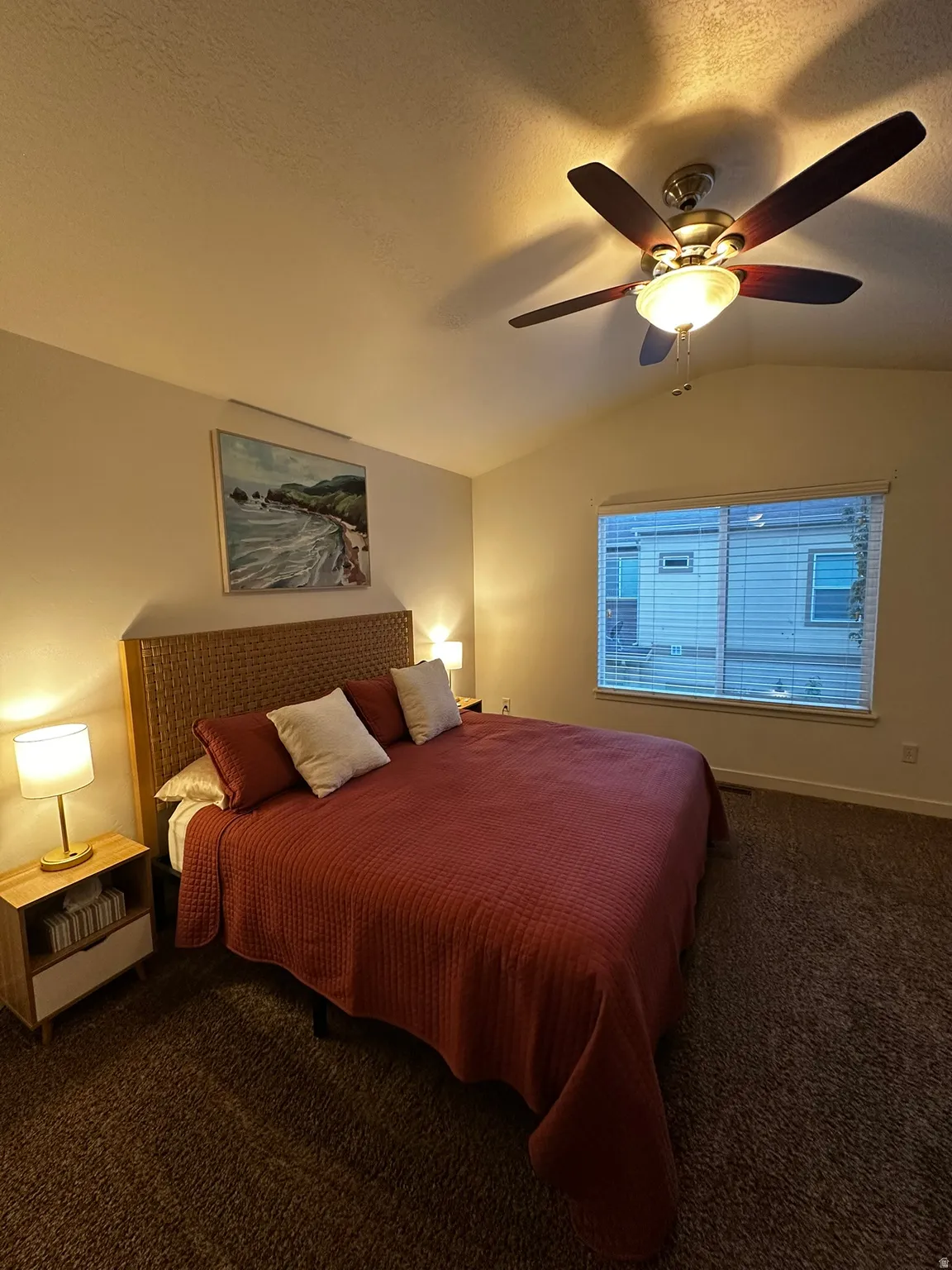 Vaulted ceiling room featuring a ceiling fan with integrated lighting, window with blinds, and carpeted flooring