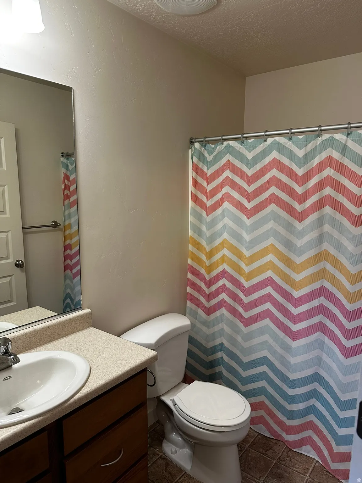 Bathroom featuring a vanity with an integrated sink, laminate countertop, and wood-finish cabinetry
