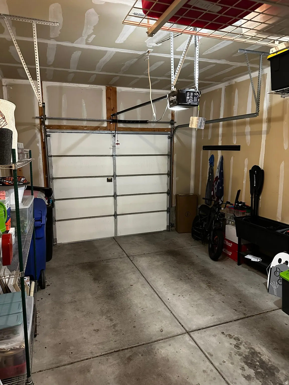 Single-car garage featuring a sectional garage door, concrete flooring, and ceiling-mounted storage racks