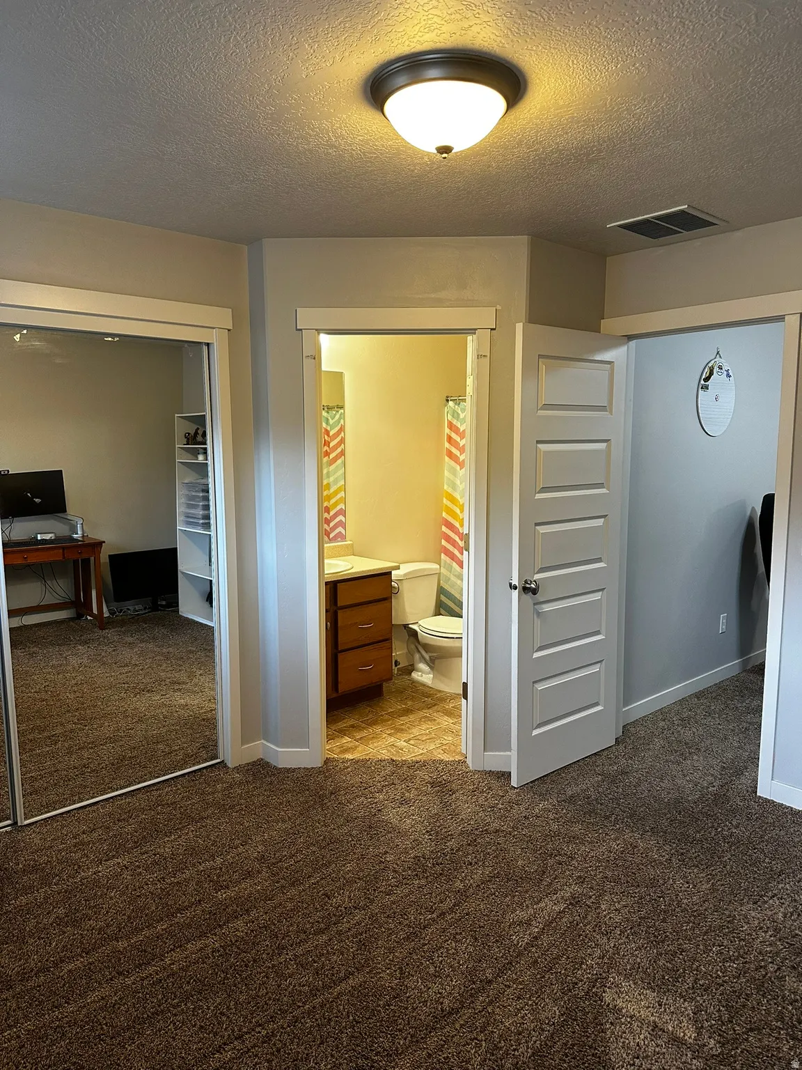 Wall-to-wall brown carpet flooring with an overhead flush mount light fixture