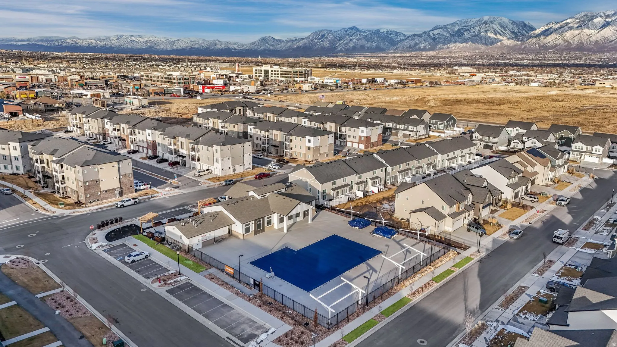 Expansive community featuring diverse residential architecture, a prominent community pool with surrounding hardscaping, and a recreation building