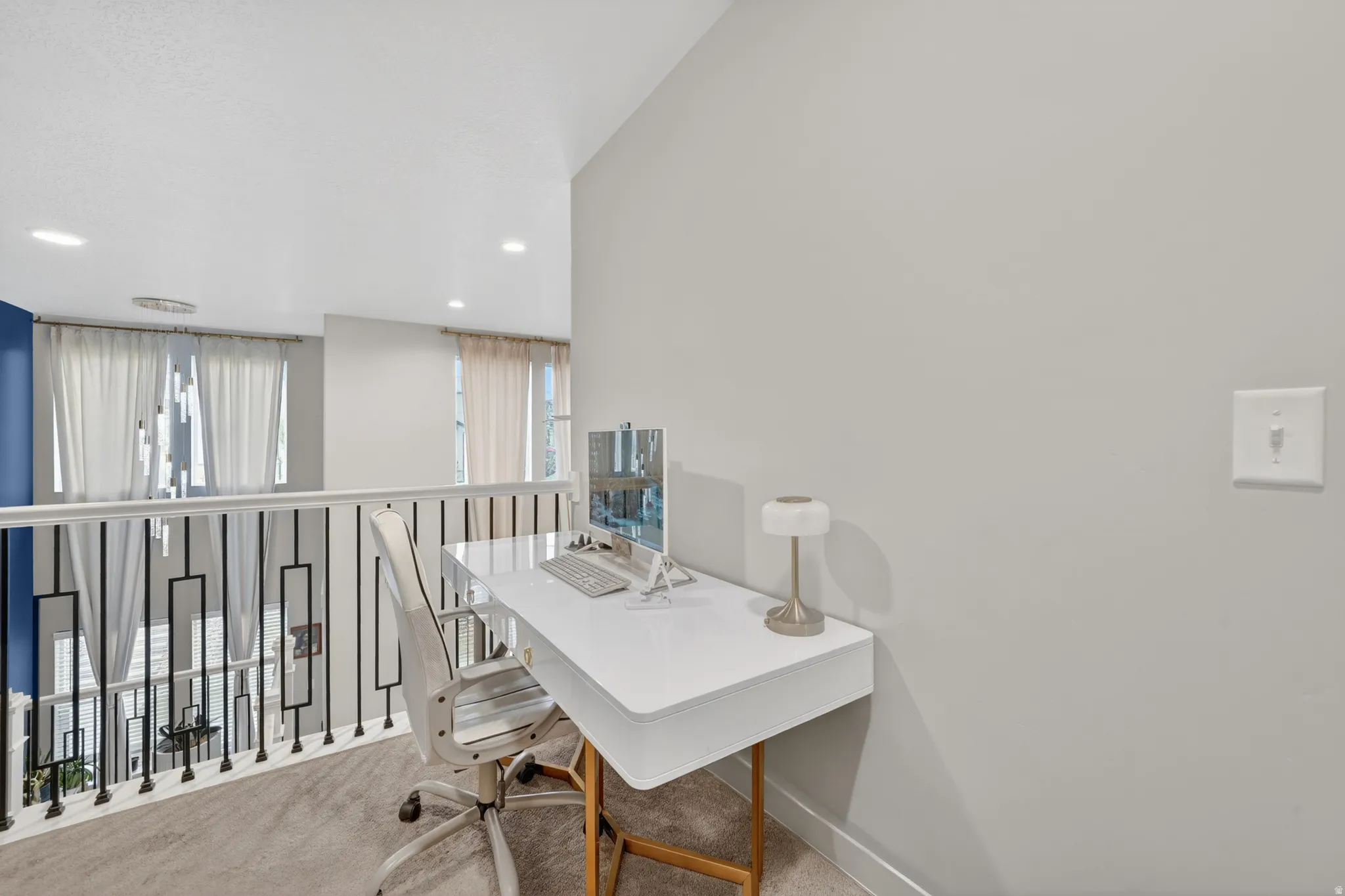 Carpeted loft area featuring a white desk, light grey walls, and a contemporary railing system with black balusters