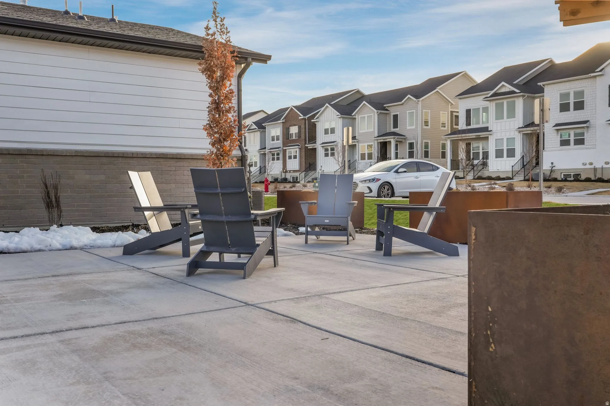 Expansive concrete patio with metal planters and landscaping
