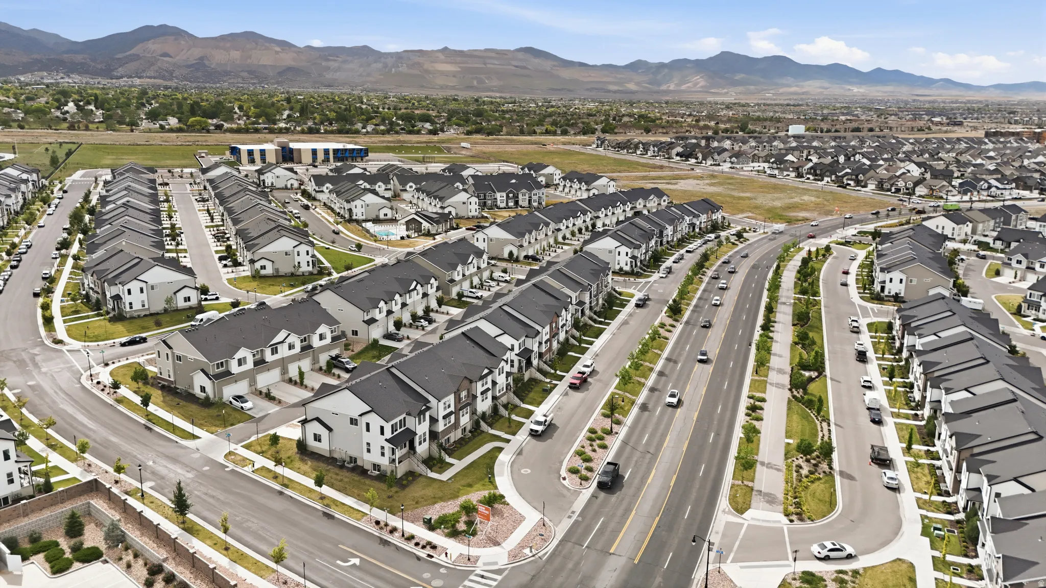 Expansive residential development featuring contemporary townhomes with multi-car garages, uniform dark roofs, and light-toned siding