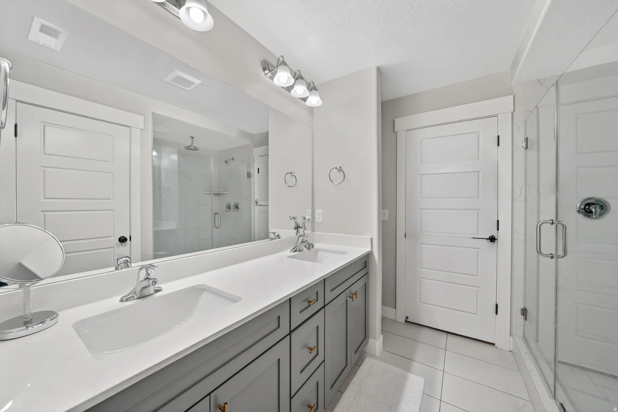 Double vanity featuring a white countertop and gray cabinetry with gold-tone hardware