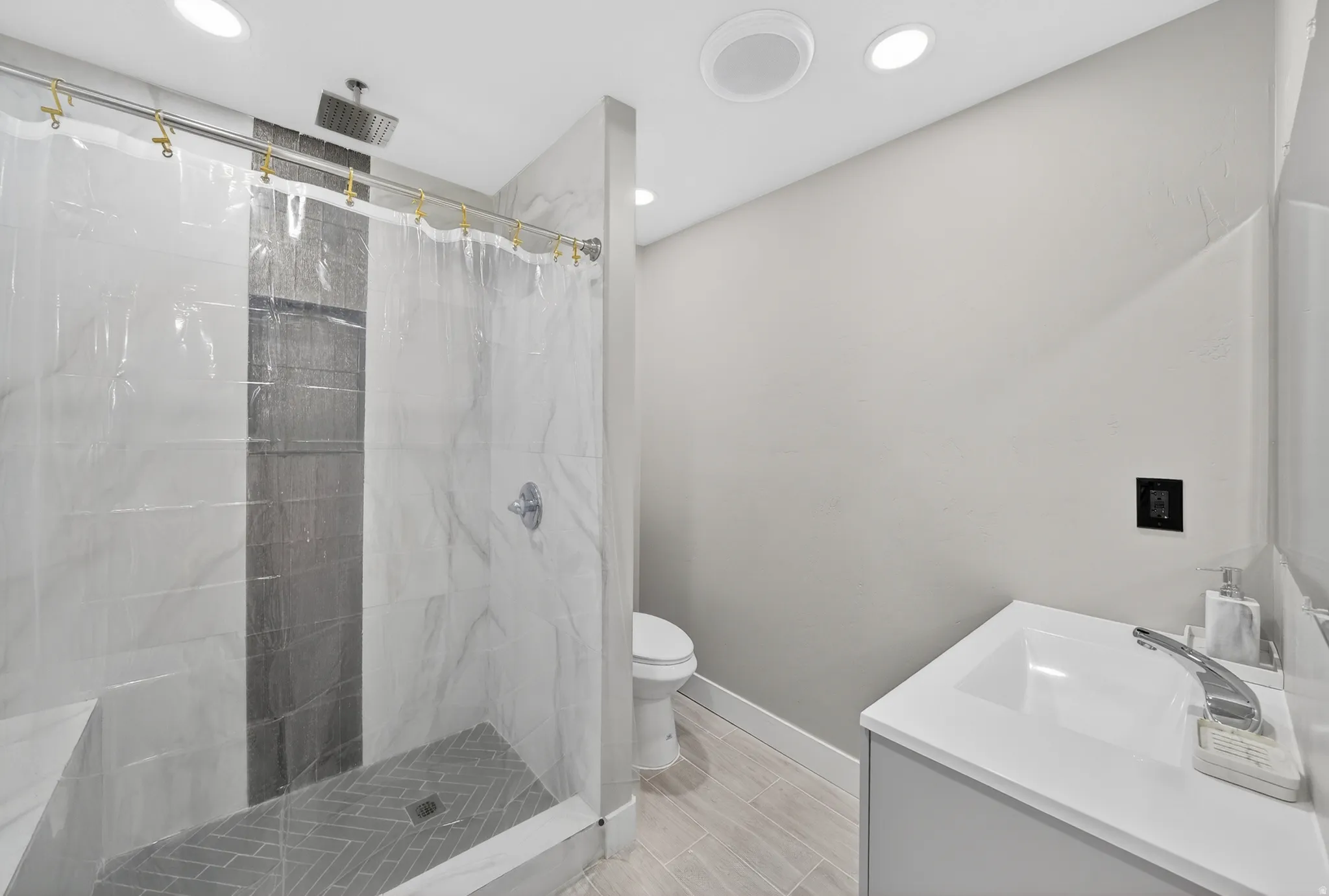 Walk-in shower with a rain shower head, herringbone pattern floor tiles, and a built-in bench