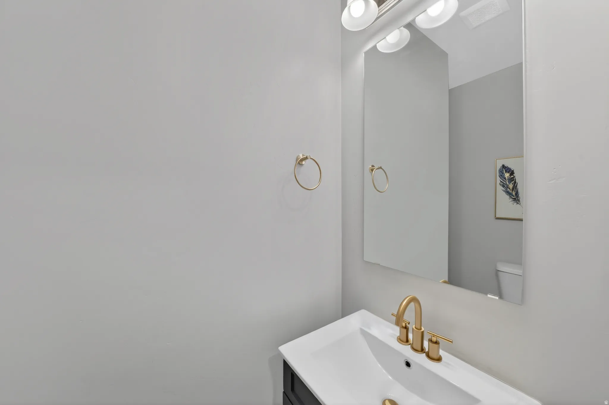 Modern vanity with an integrated white sink, gold-finish faucet, and coordinating gold-finish towel ring