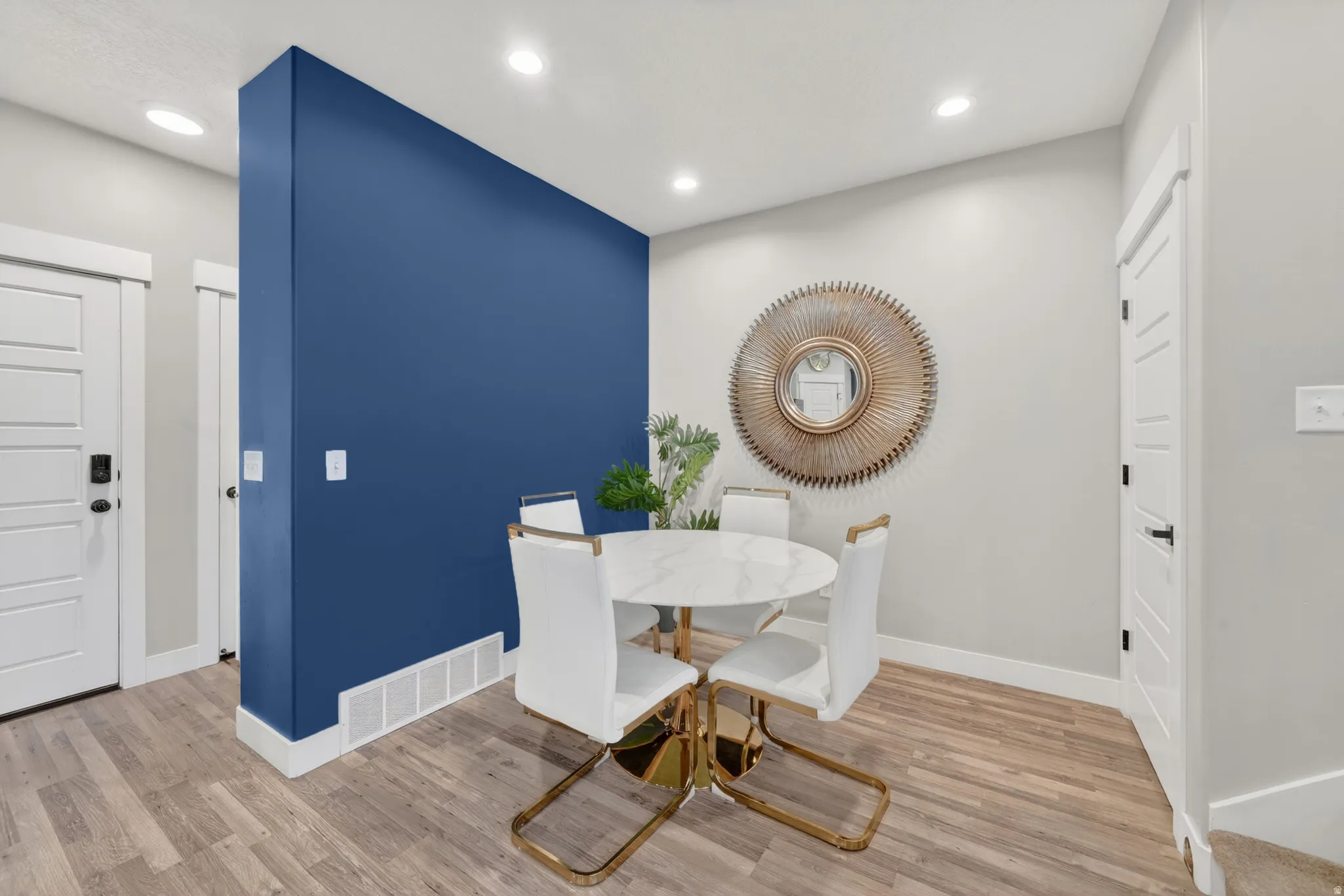 Recessed lighting illuminates a blue accent wall and wood-finish flooring