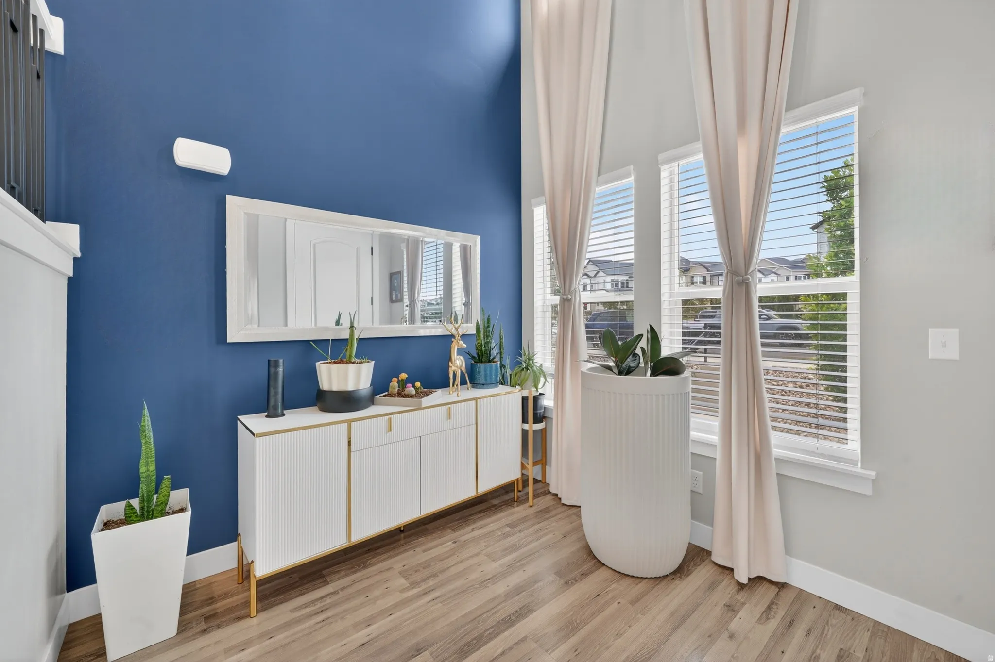 Two-story entry featuring wood-finish flooring, a contemporary white console with gold accents, and a large rectangular mirror