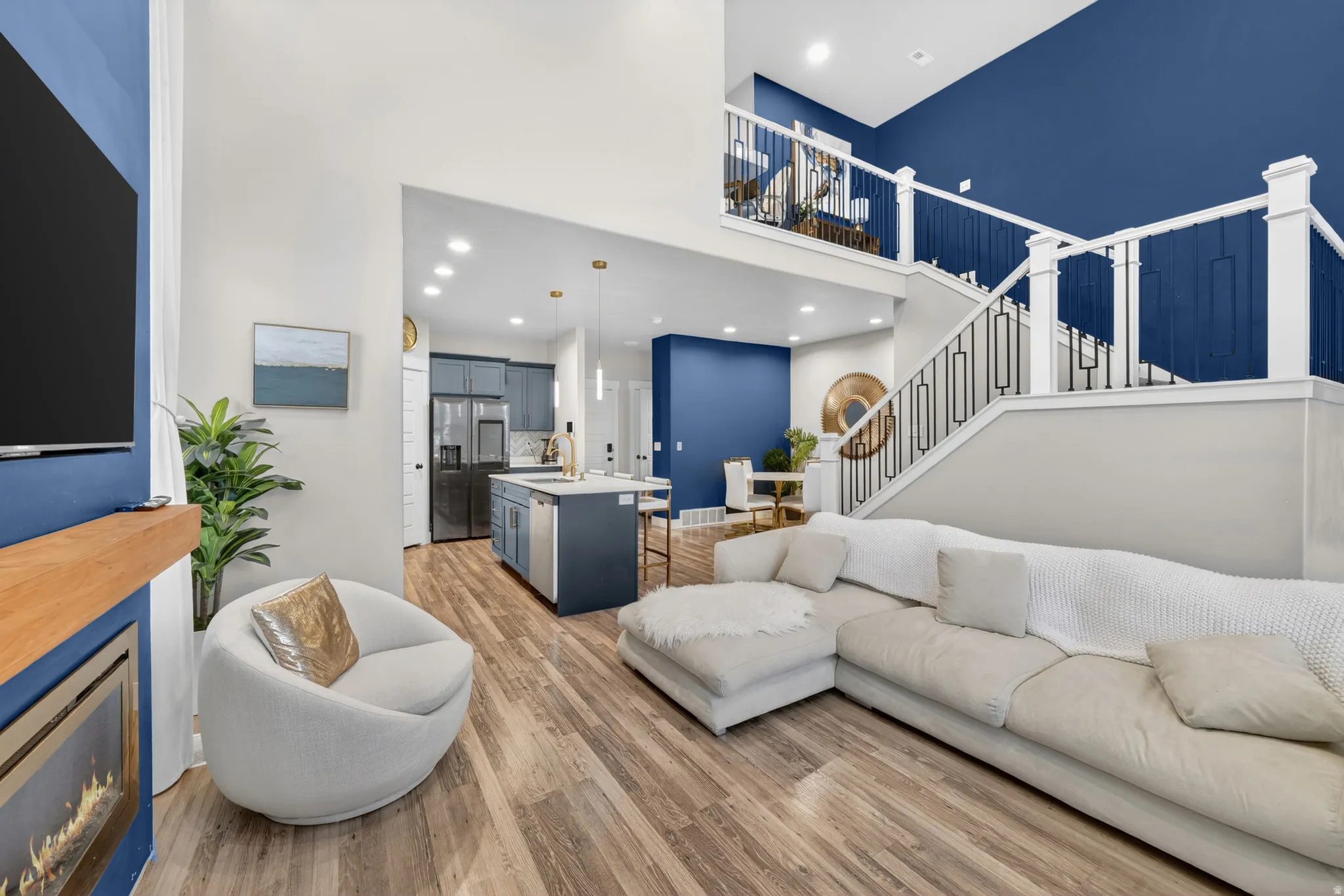 Open-concept living area featuring high ceilings, wood-finish flooring, and a contemporary fireplace with a wood mantle