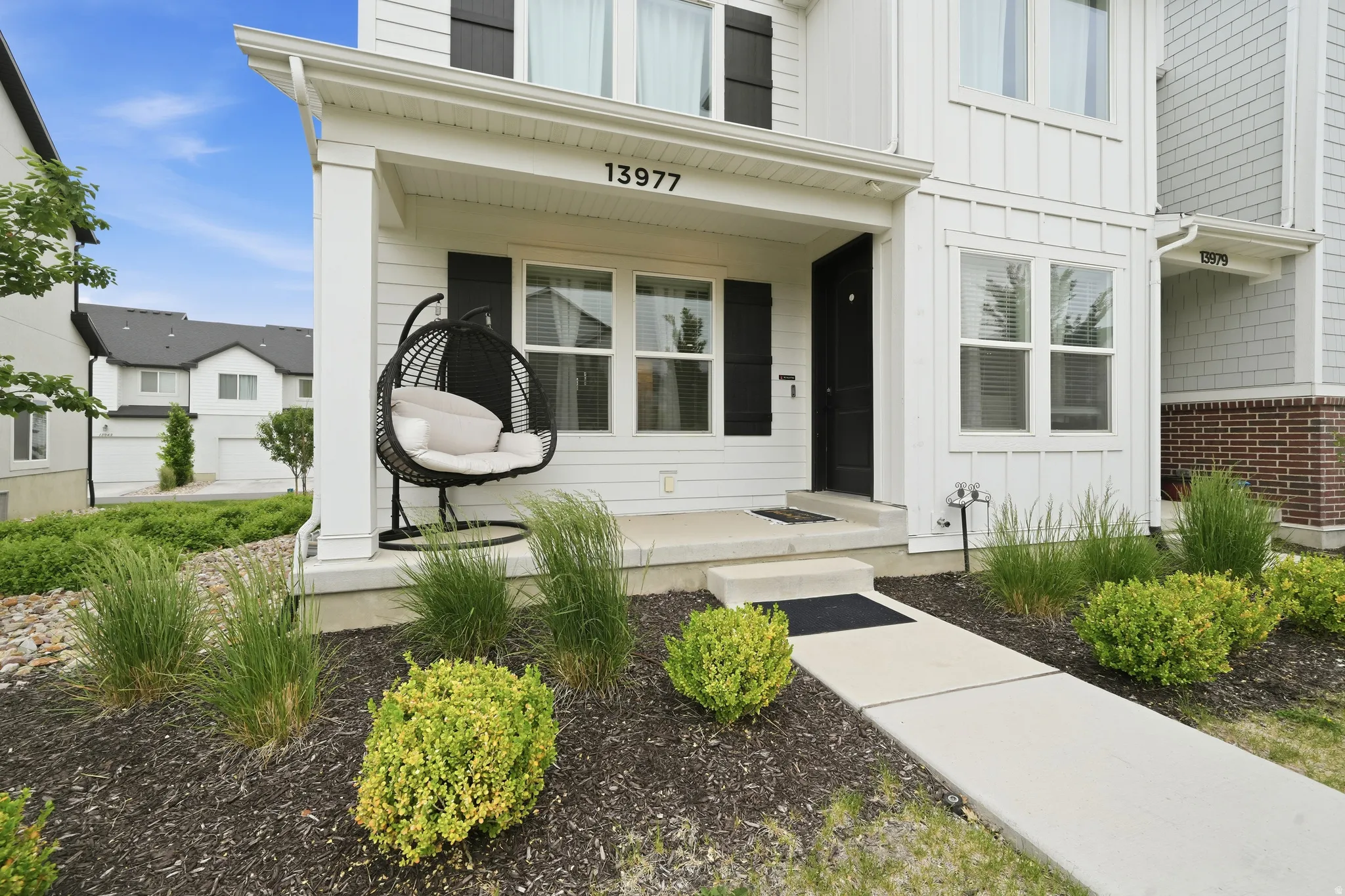Modern farmhouse-style exterior with white vertical siding and black window shutters