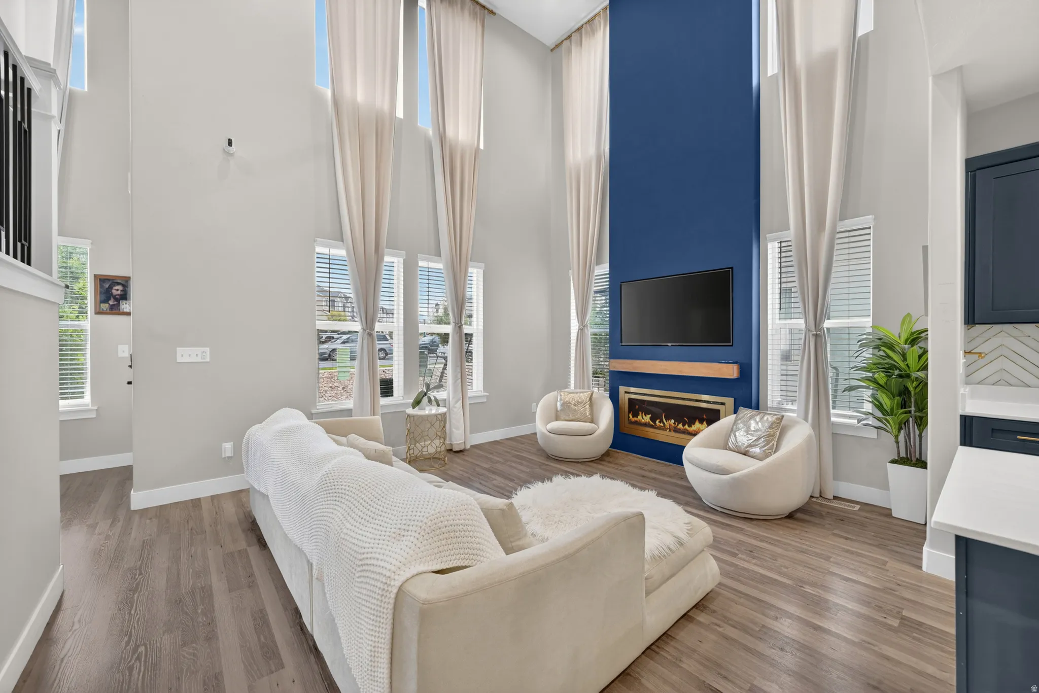 Vaulted living area featuring a dramatic blue accent wall with an integrated fireplace and wood mantel