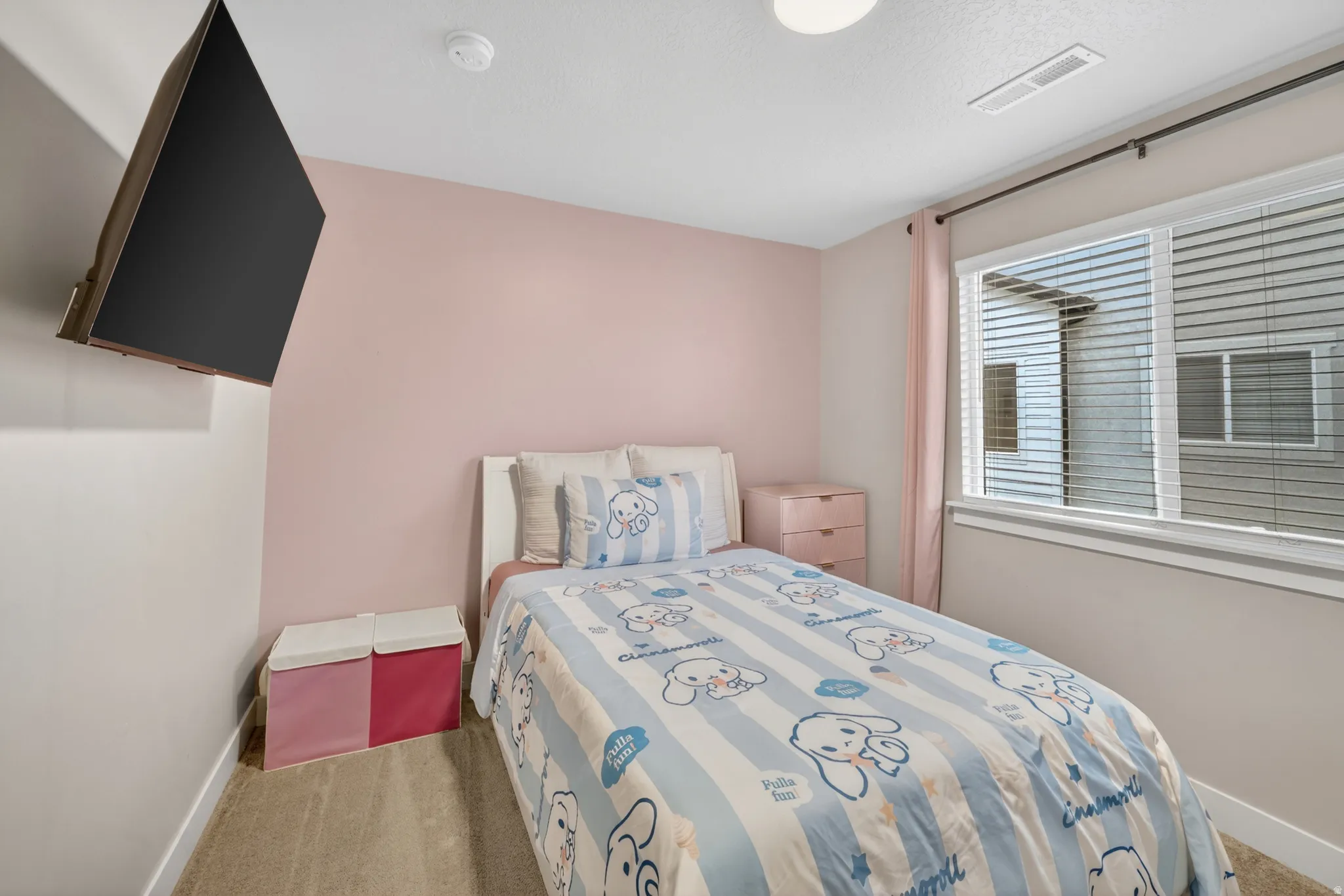 Bedroom featuring a wall-mounted television, neutral carpeting, and a window with blinds