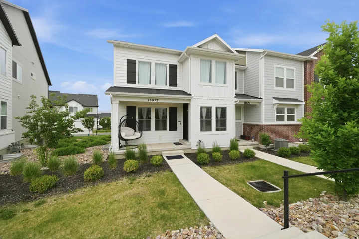 Two-story property featuring a white vertical siding facade with black window shutters