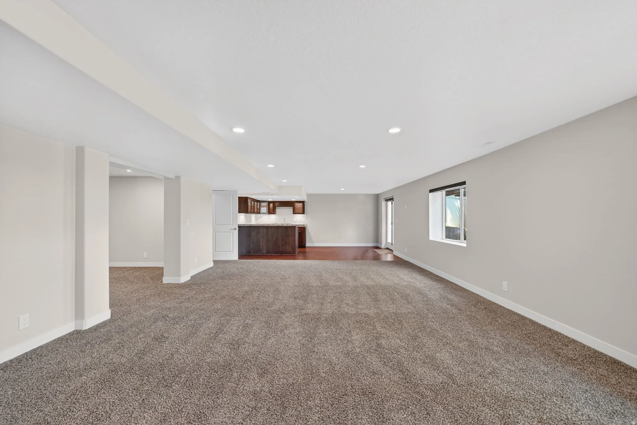 Spacious open-concept living area featuring plush carpet flooring and recessed lighting