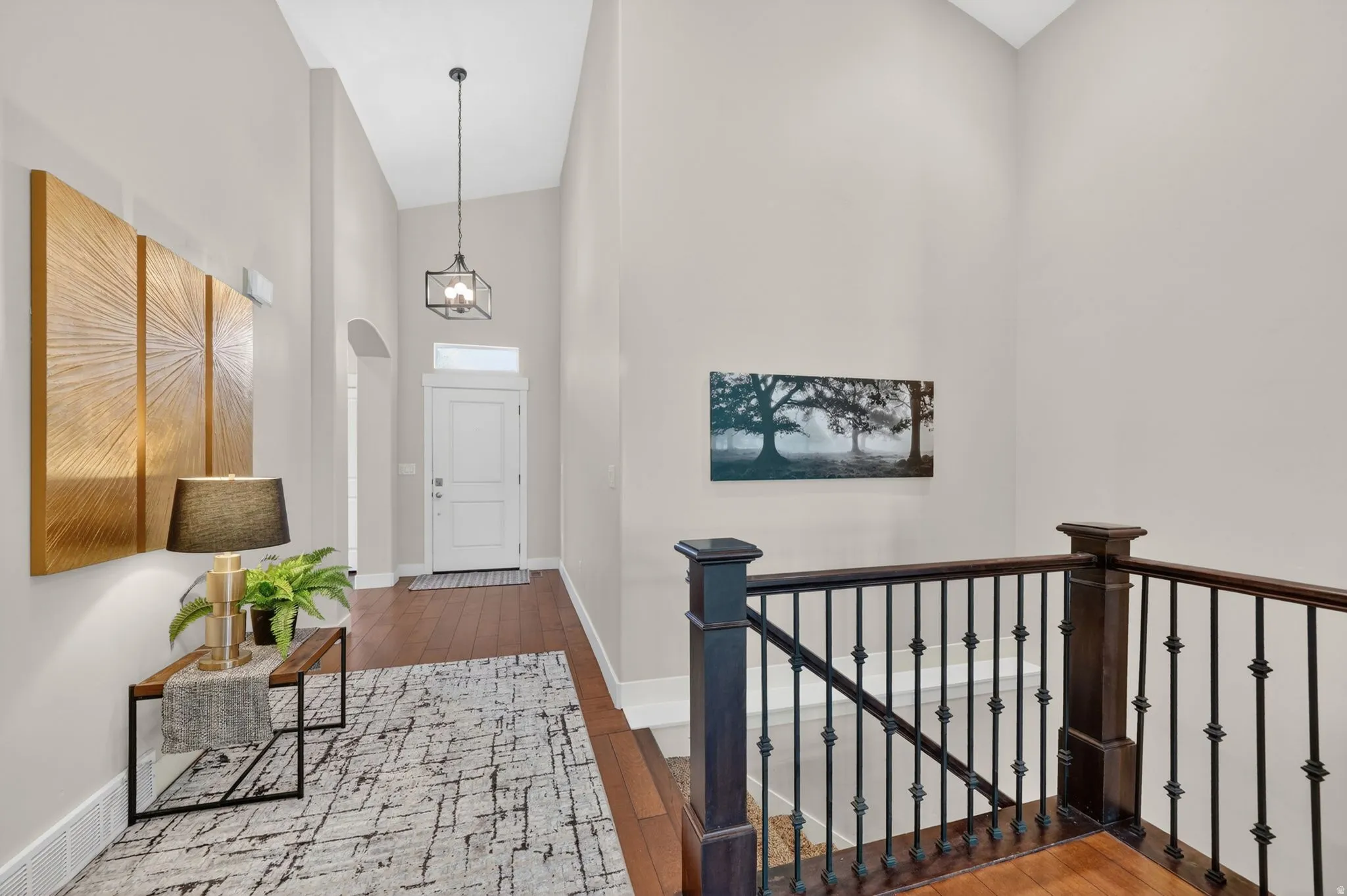 Foyer with double-height ceiling, wood-finish flooring, and an arched entry