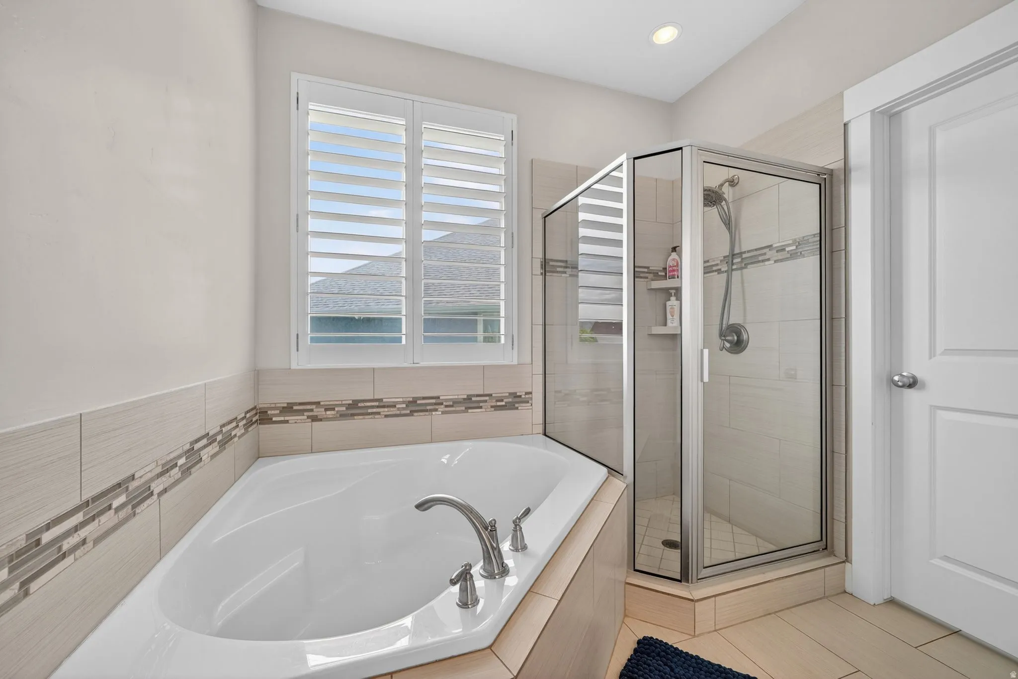 Soaking tub with polished chrome fixtures, accented by decorative tile banding