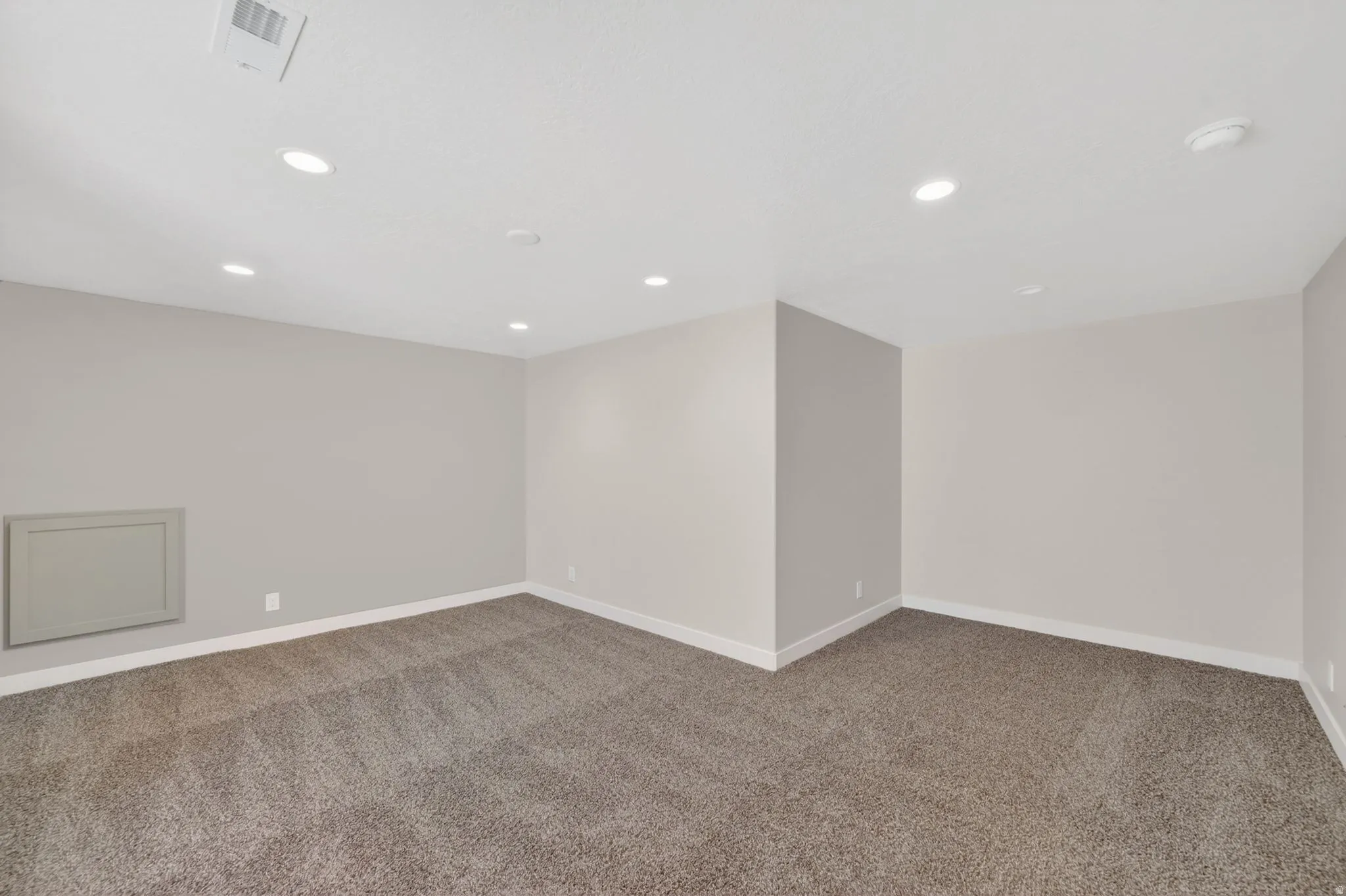 Spacious room featuring neutral carpeting, light neutral wall paint, white baseboards, recessed lighting, and a white ceiling