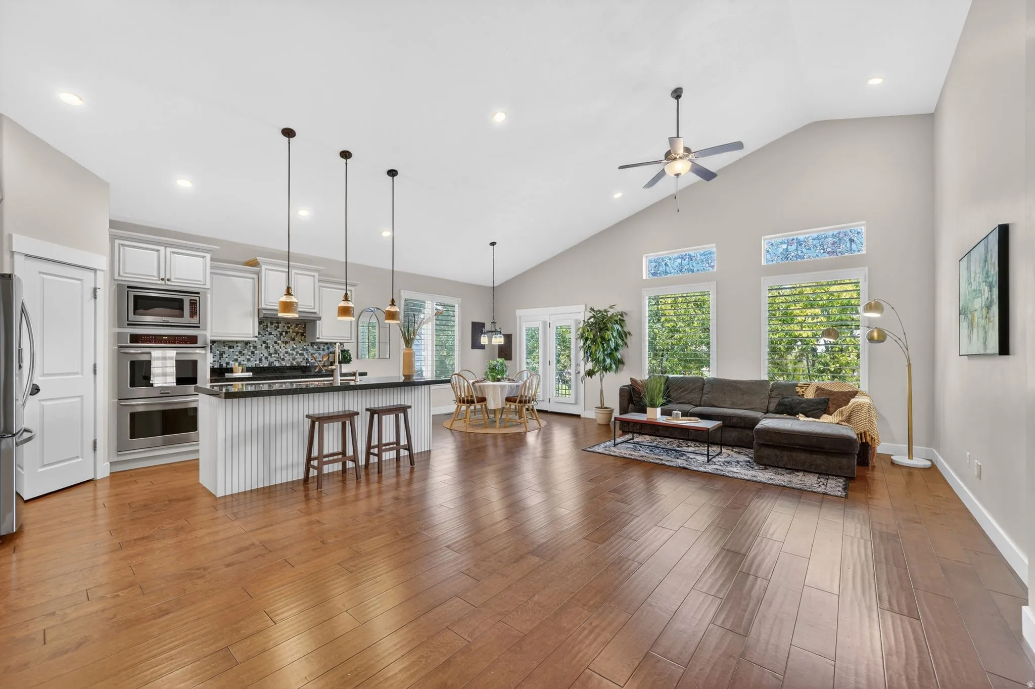 Open-concept living space featuring wood-finish flooring, vaulted ceilings, and recessed lighting