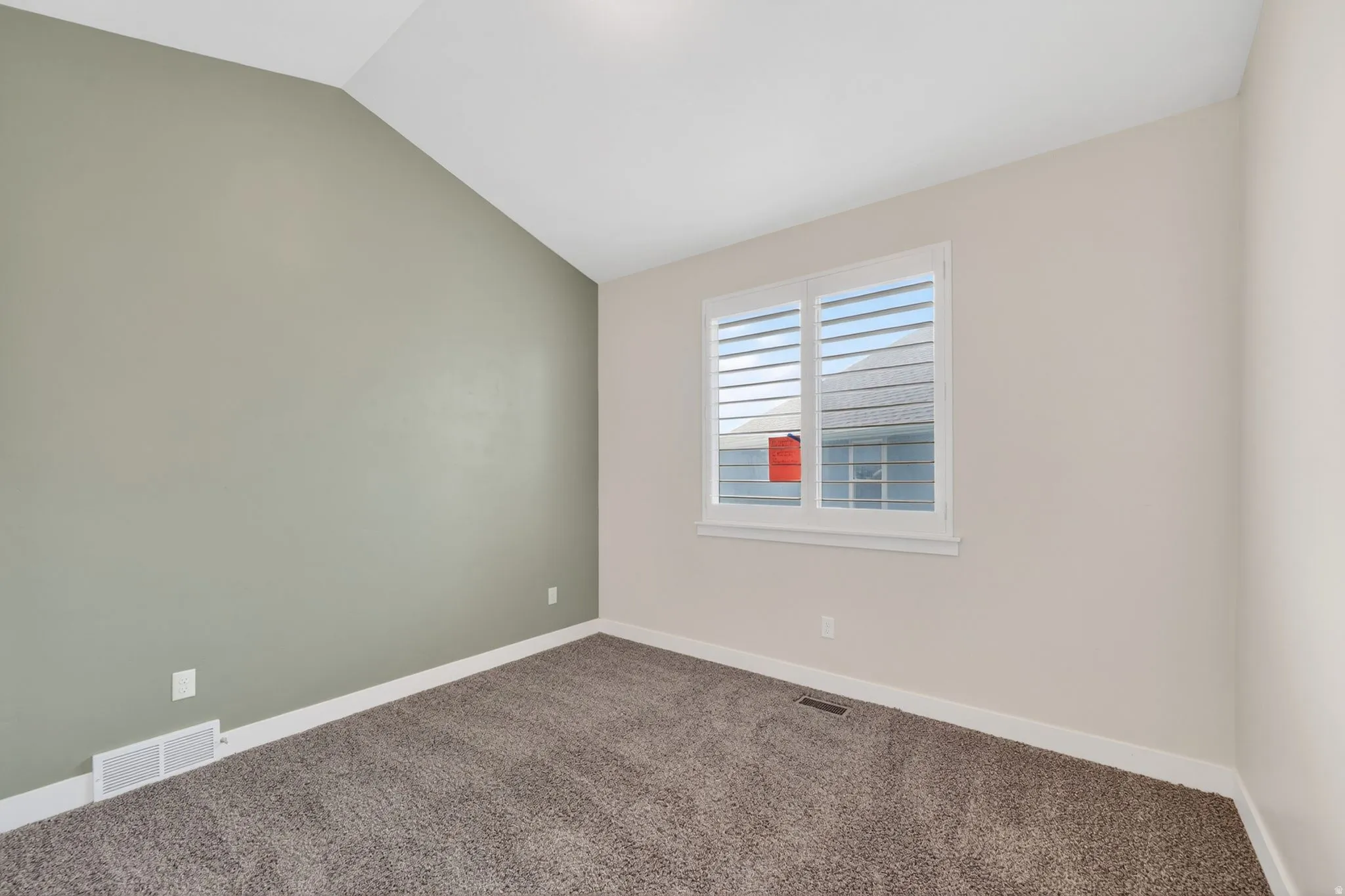 Room featuring a vaulted ceiling, two-tone wall paint, white baseboards, and a window with white plantation shutters