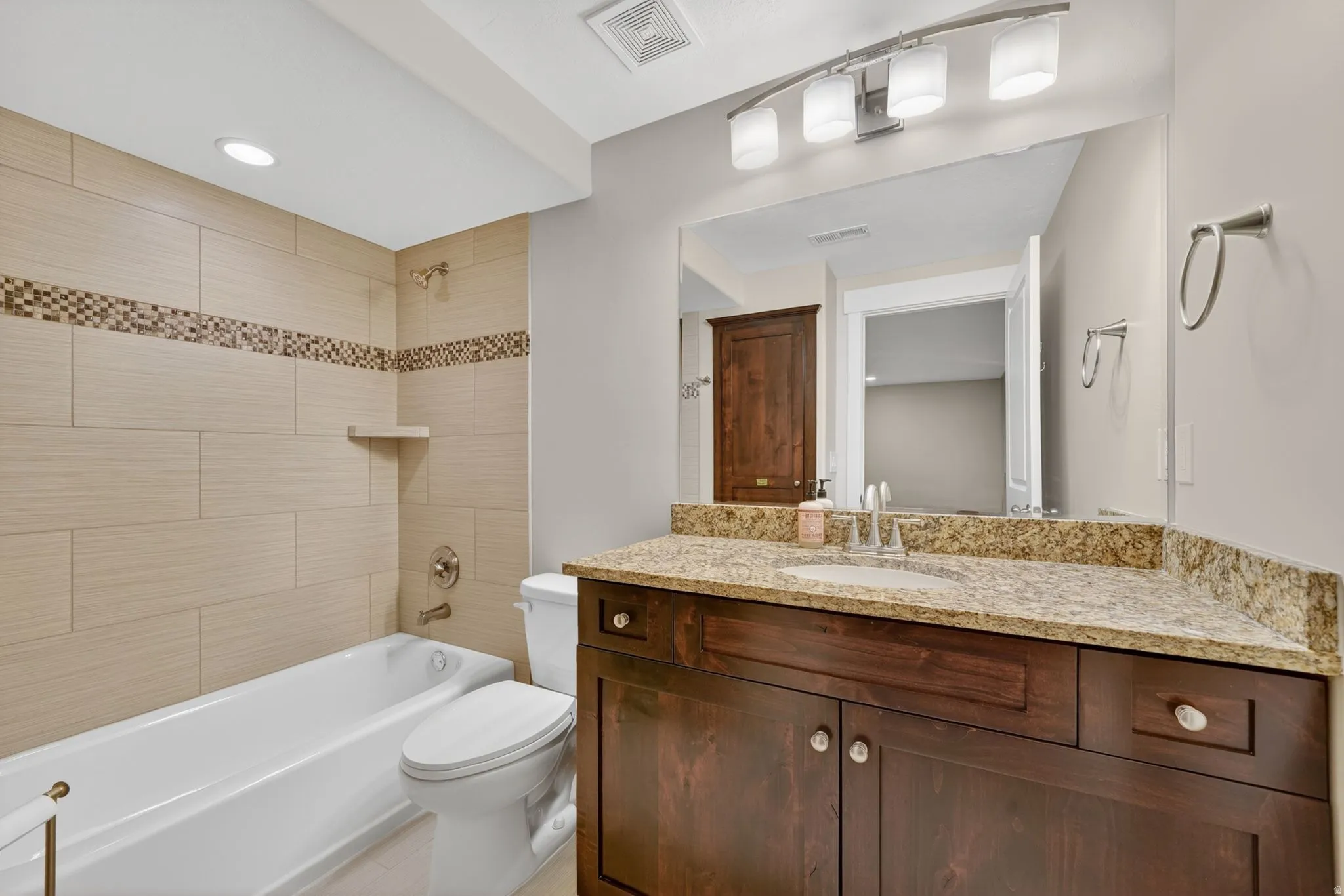 Bathroom featuring a dark wood-finish vanity with a light-toned countertop, an integrated sink, and a framed mirror