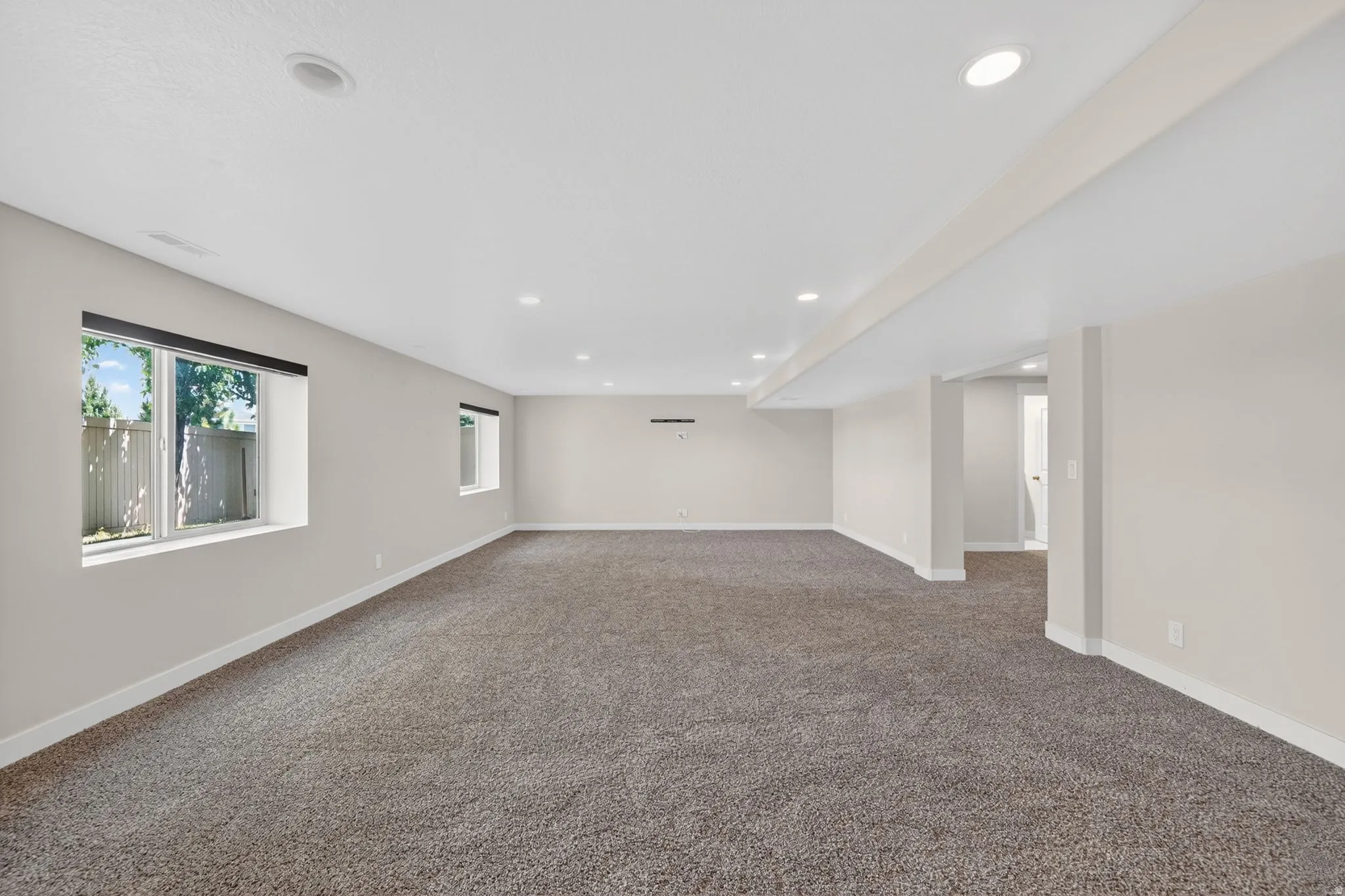 Spacious open-concept room featuring plush carpet flooring and recessed ceiling lighting