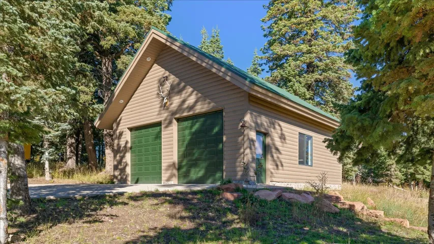 Two-car garage with green doors, beige siding, and a green roof
