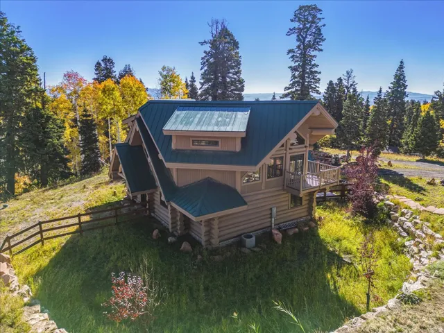 Log home featuring a dark green metal roof and an upper-level balcony