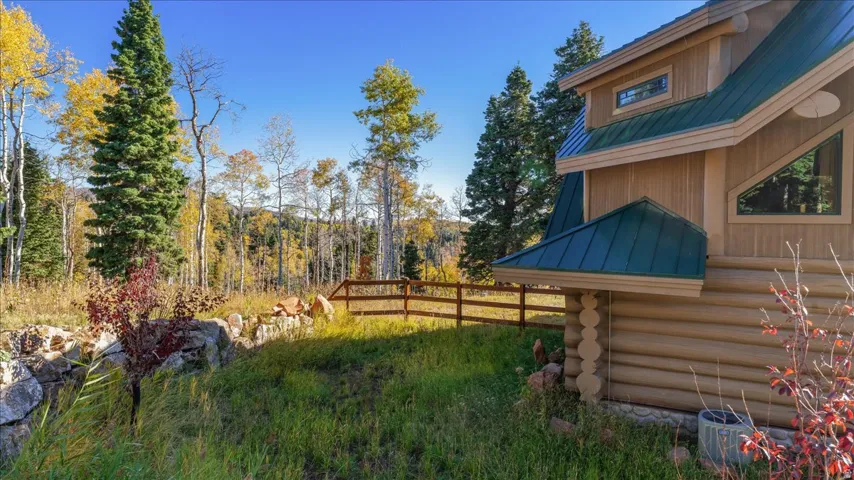 Log cabin exterior featuring a green metal roof, natural wood siding, and prominent triangular windows