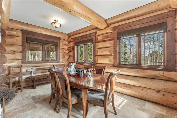 Log cabin interior featuring exposed wood beams, wood paneling, and natural wood window frames