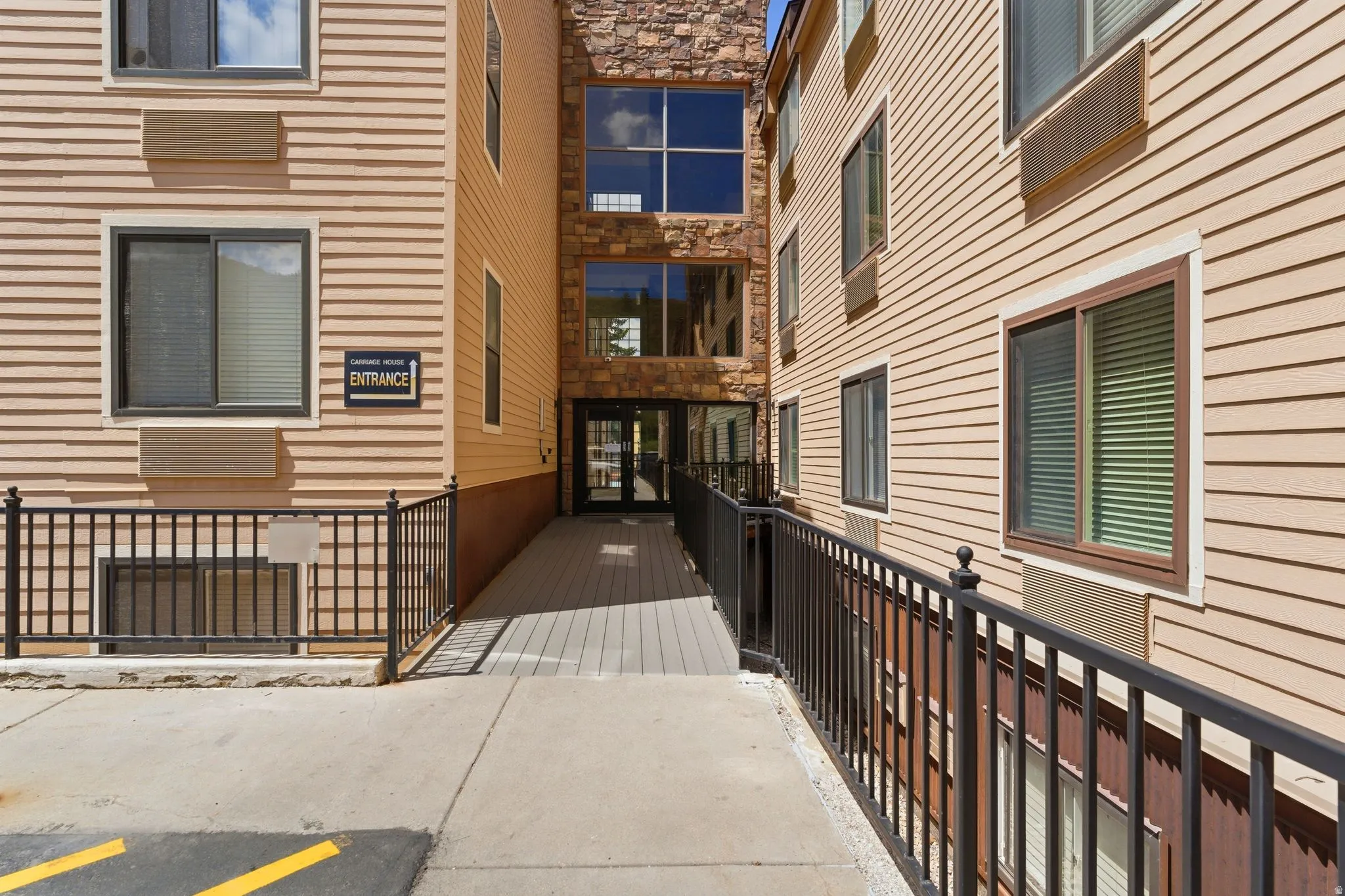 Exterior facade featuring horizontal siding and stone accents, with a ramped entrance leading to a glass-paneled doorway