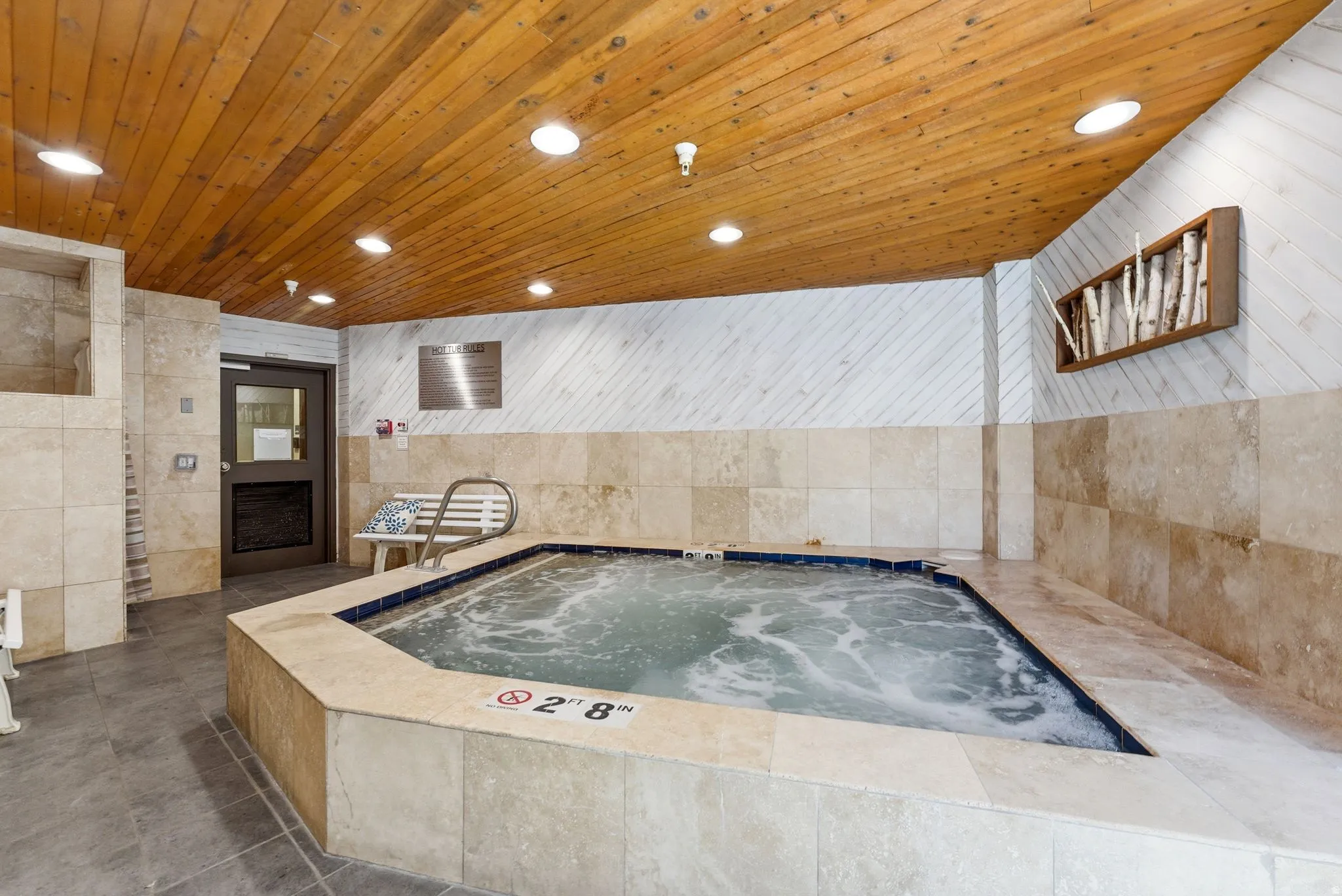 Indoor hot tub featuring a tile surround and blue tile interior