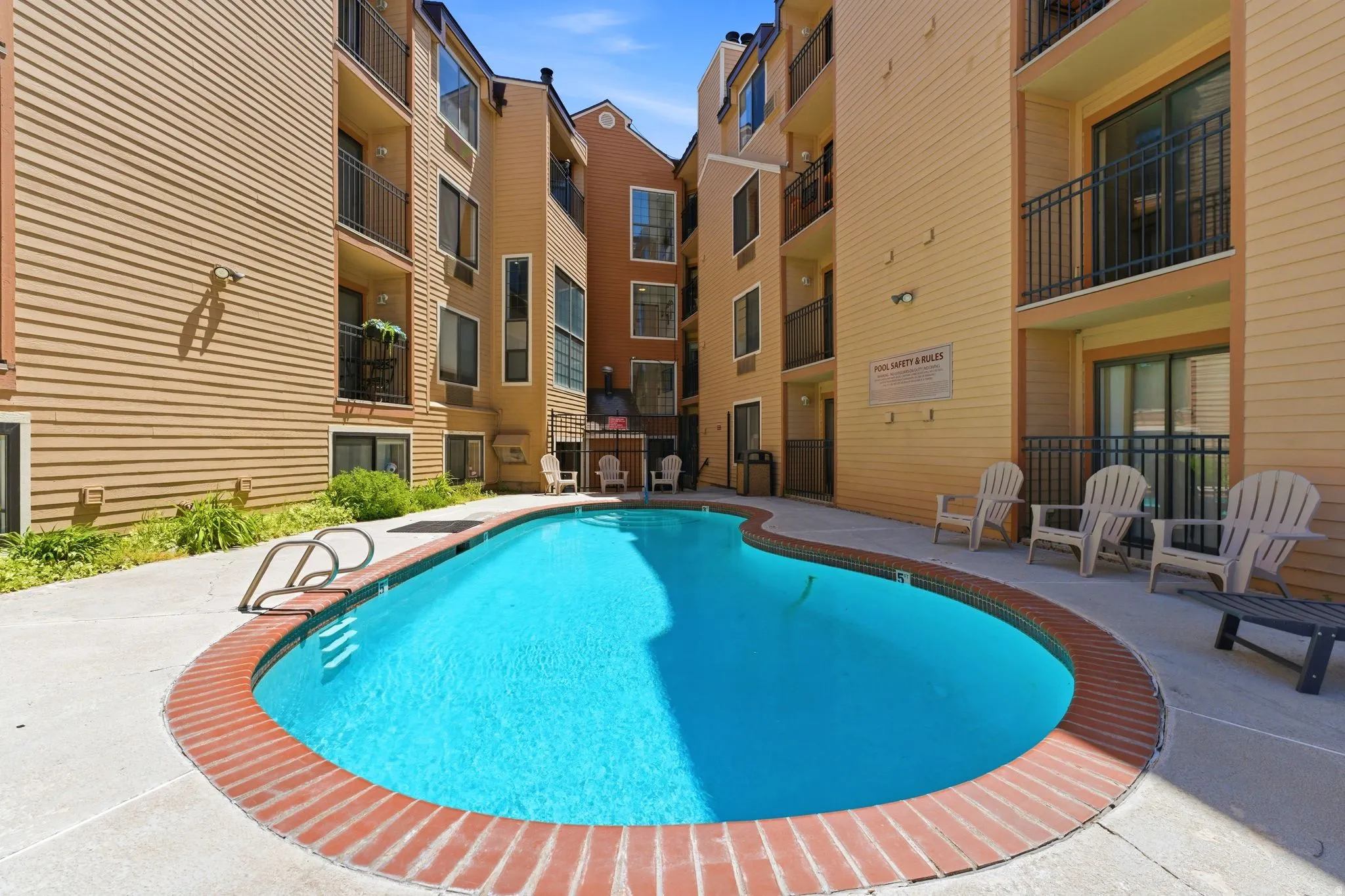 Curved swimming pool with a brick coping, surrounded by a concrete patio