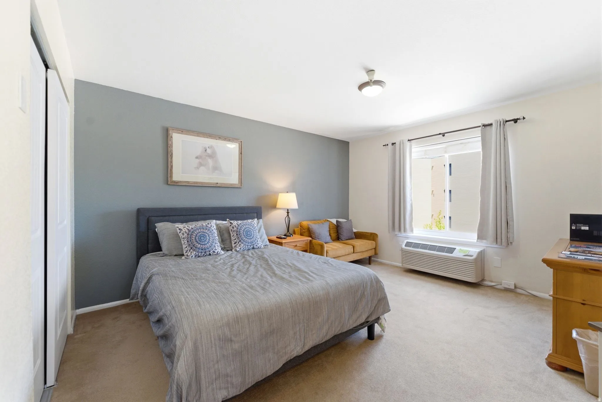Neutral-toned carpet flooring complements the light-colored walls and grey accent wall