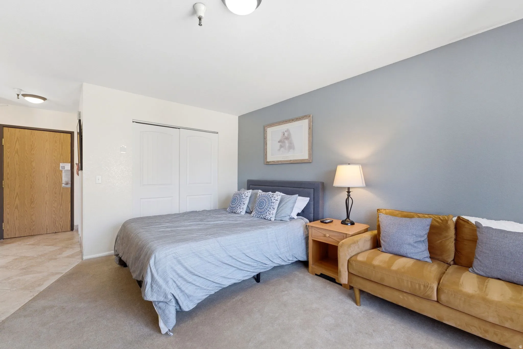 Bedroom featuring light gray carpeting, a two-door closet with paneling, and an accent wall