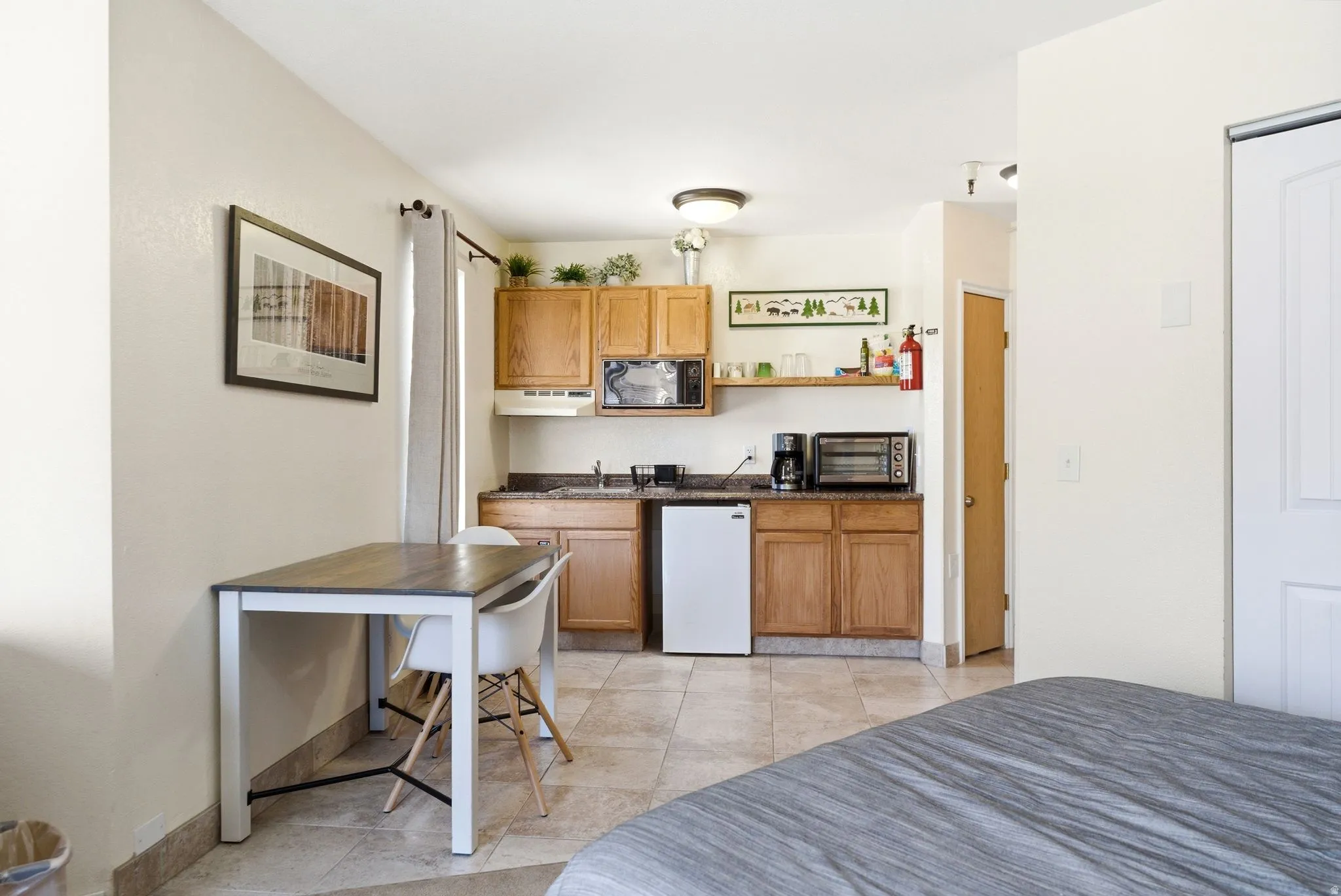 Efficient kitchen area featuring wood cabinetry, a microwave, and a compact refrigerator
