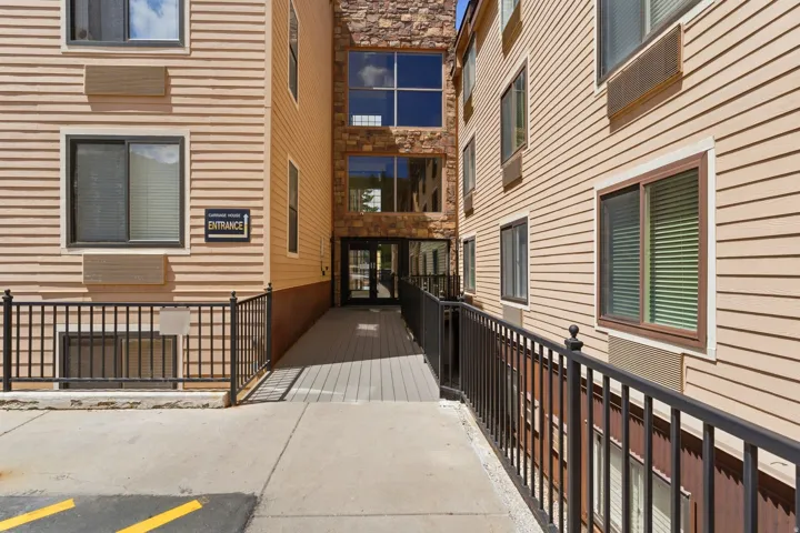 Exterior facade featuring horizontal siding and stone accents, with a ramped entrance leading to a glass-paneled doorway