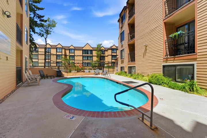 Inviting outdoor pool with a curved design, surrounded by a concrete deck and brick coping