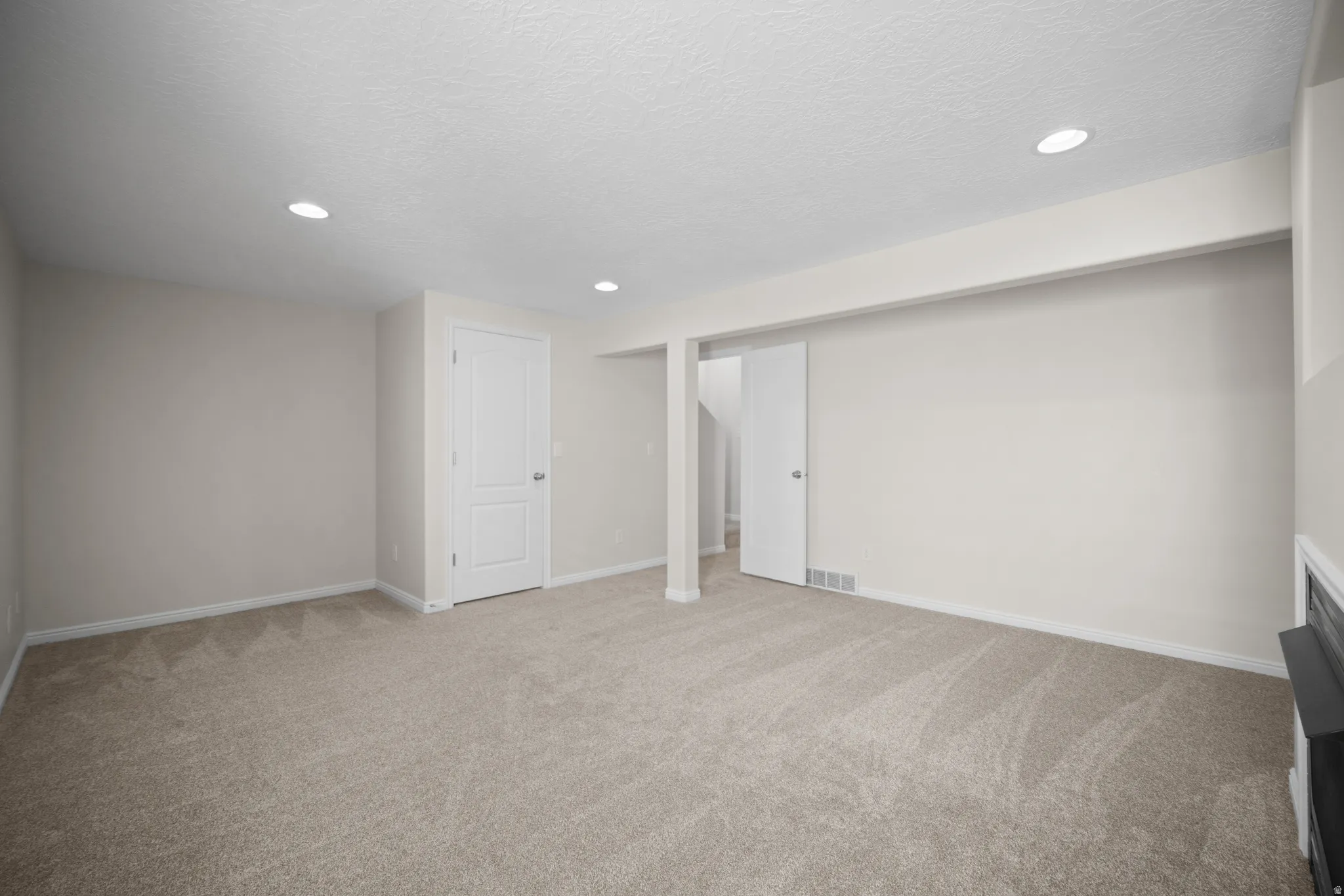 Spacious room featuring neutral carpeting, recessed lighting, white trim, and light-colored walls