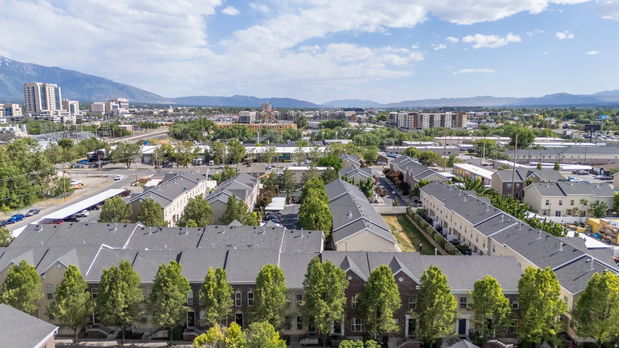 Aerial perspective showcasing a community of townhome-style residences with a mountainous backdrop