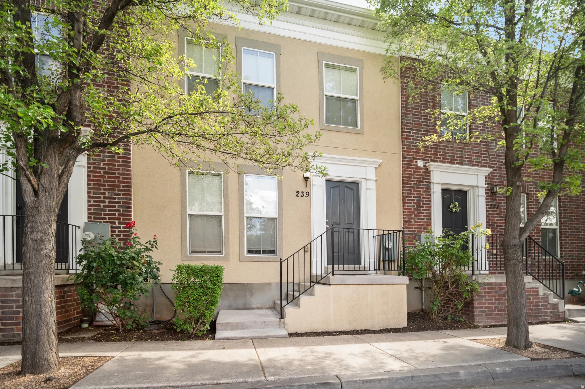 Multi-story stucco and brick exterior featuring a recessed entry with a dark paneled door