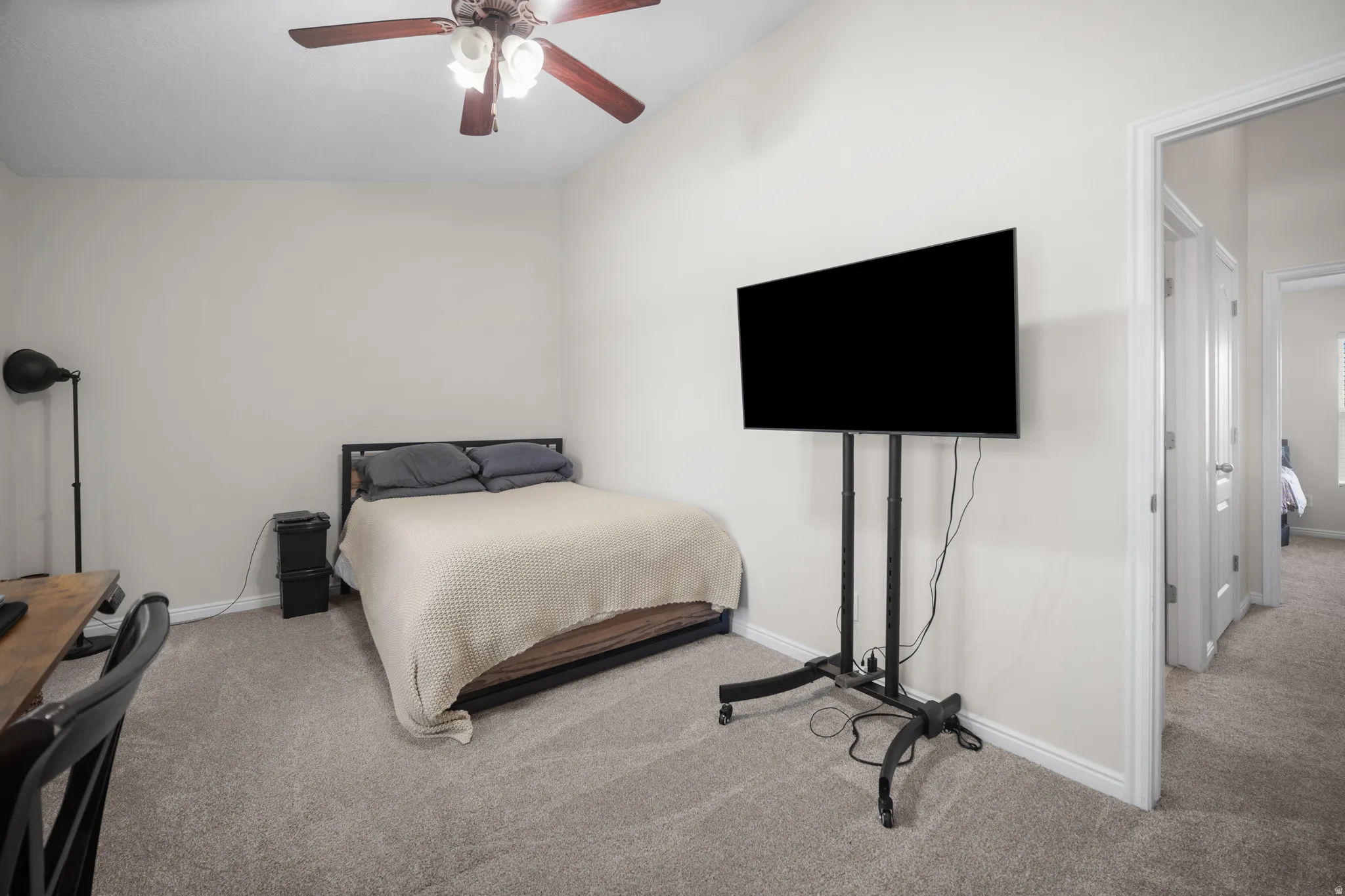 Carpeted room featuring a ceiling fan with integrated lighting, a doorway opening to a hallway, and neutral wall tones