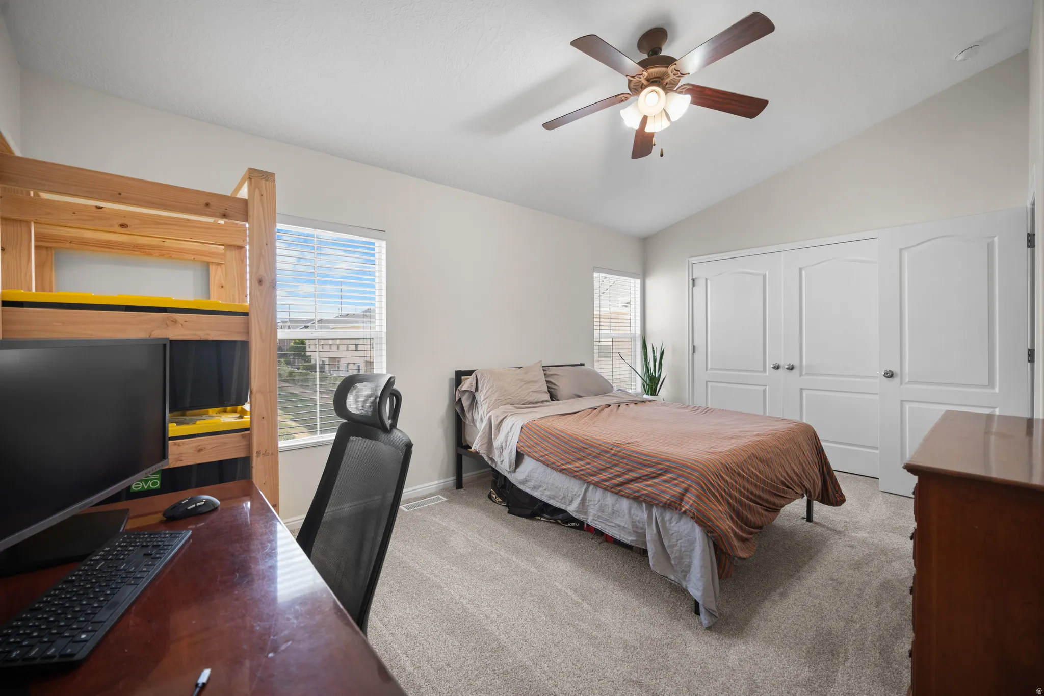 Vaulted ceiling room featuring carpet flooring, a ceiling fan with integrated lighting, and multiple windows with blinds