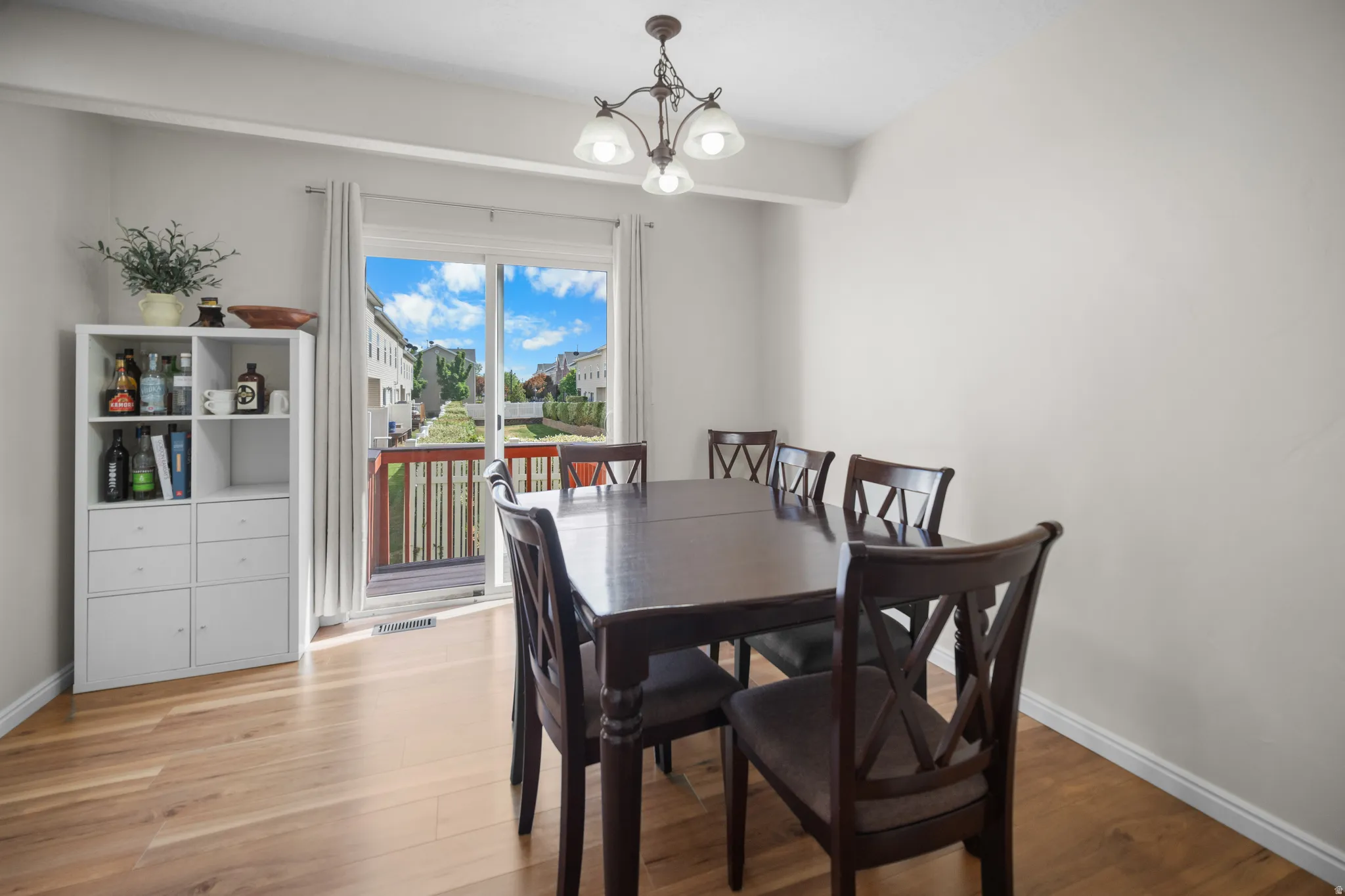 Dining area with wood-finish flooring, light-toned walls, and a sliding glass door leading to a private deck