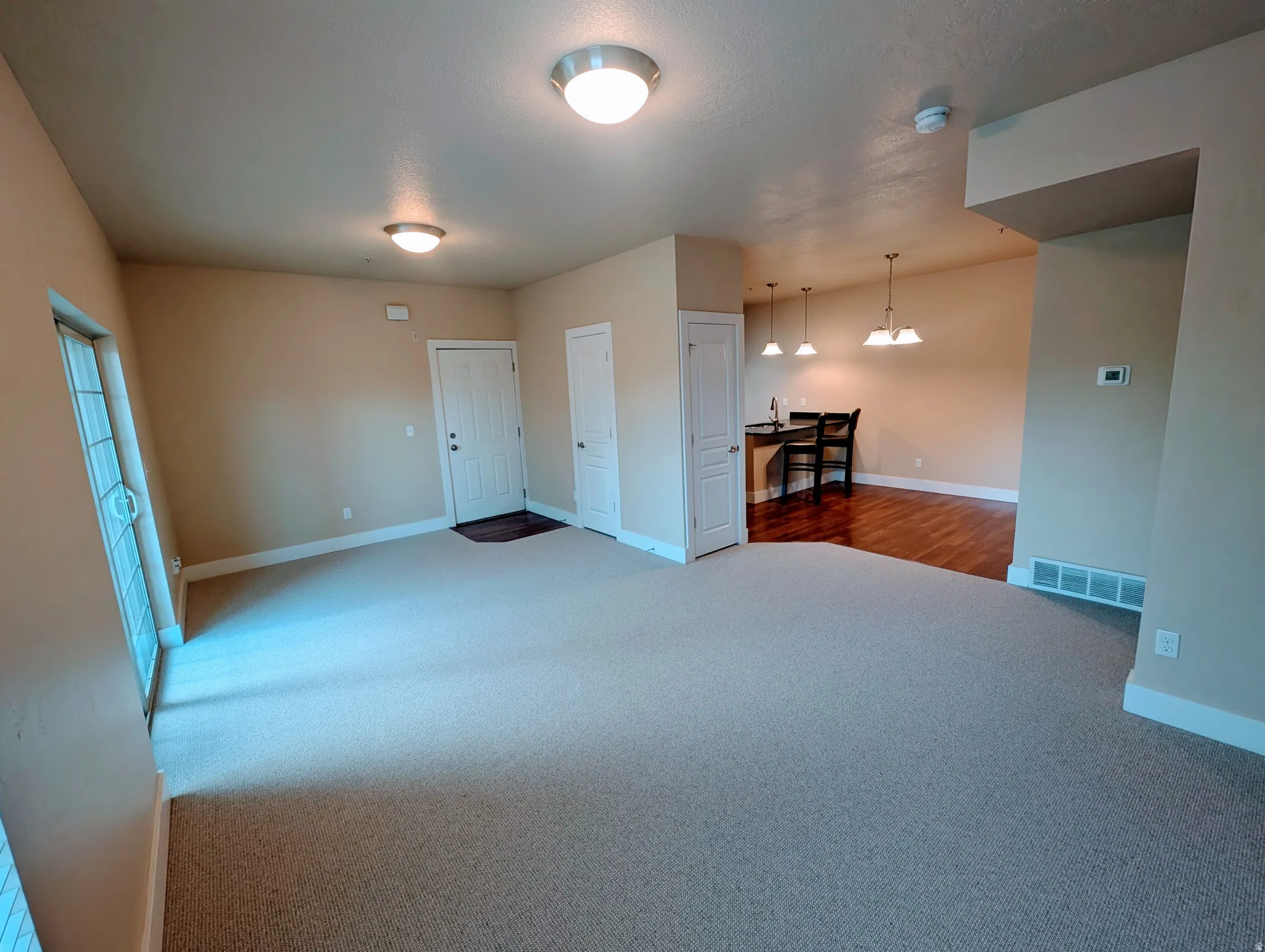 Open-concept living space featuring neutral carpet flooring and light beige wall paint
