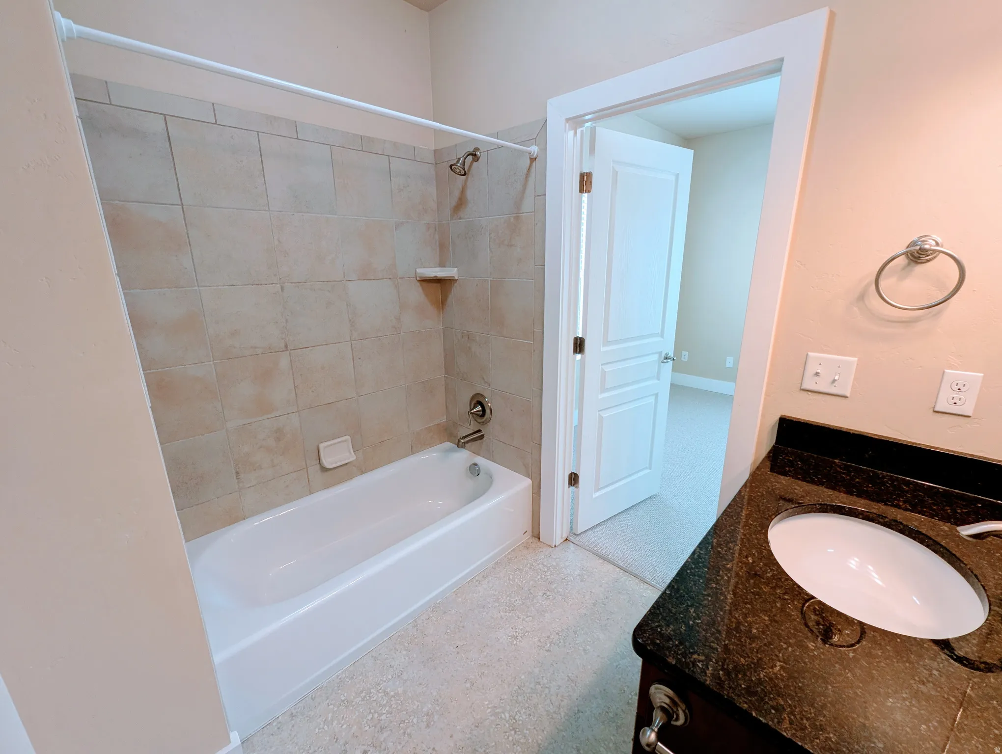 Bathroom featuring a dark wood-finish vanity with an integrated sink, a dark speckled countertop, and brushed nickel hardware