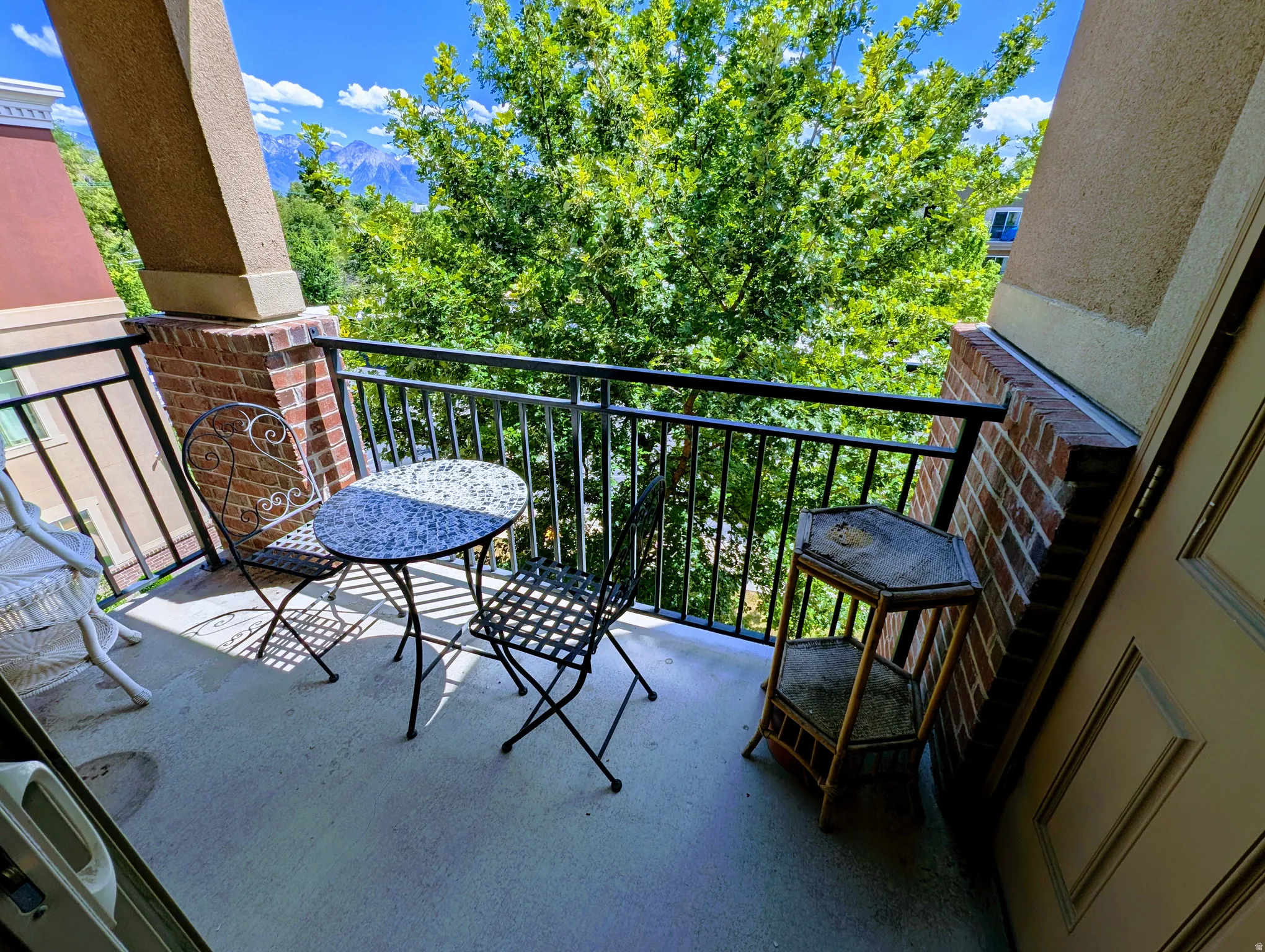 Outdoor balcony featuring a concrete floor, dark metal railings, and a brick half-wall