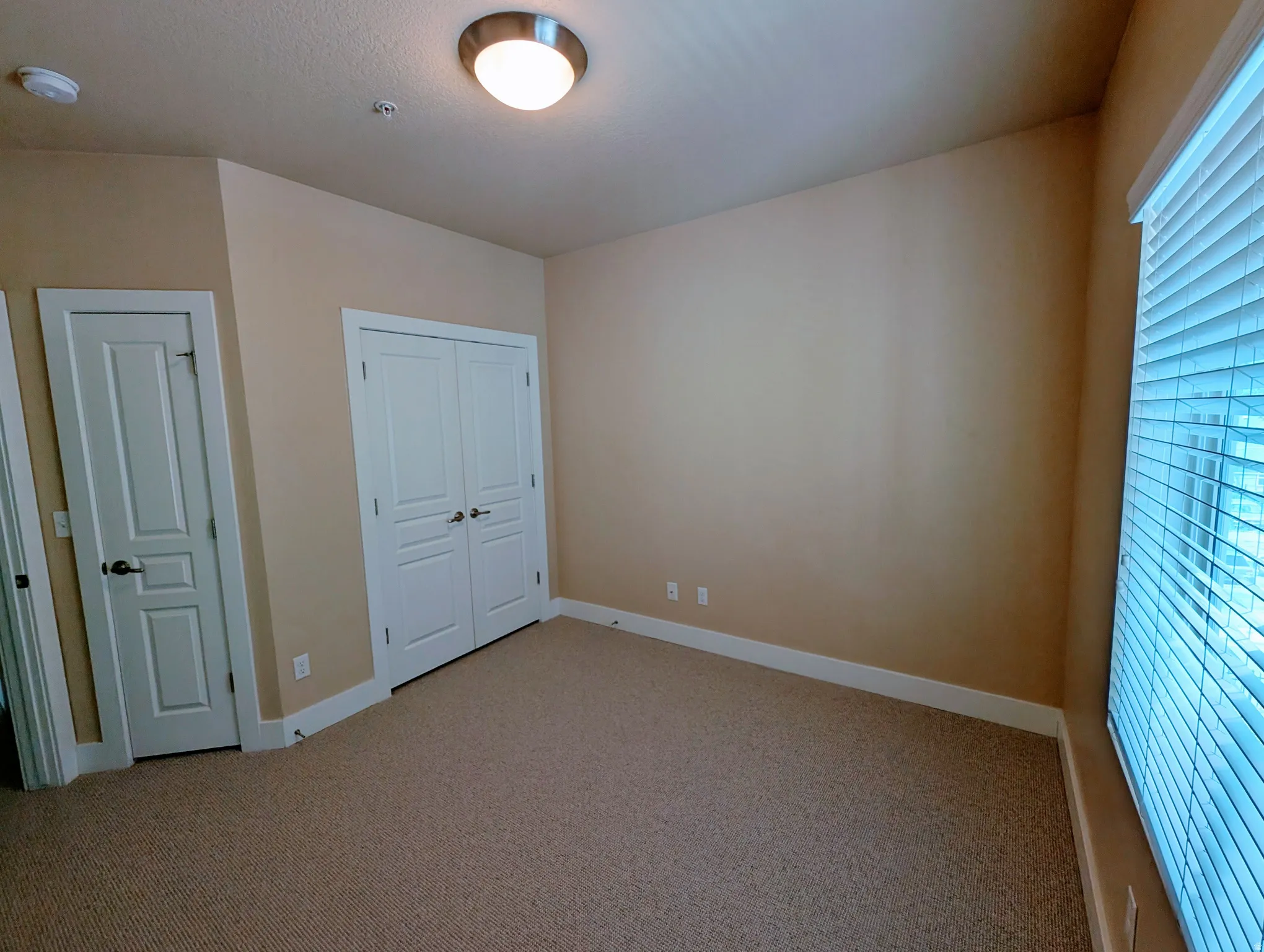 Carpeted room featuring neutral-toned walls, white trim, and a window with blinds